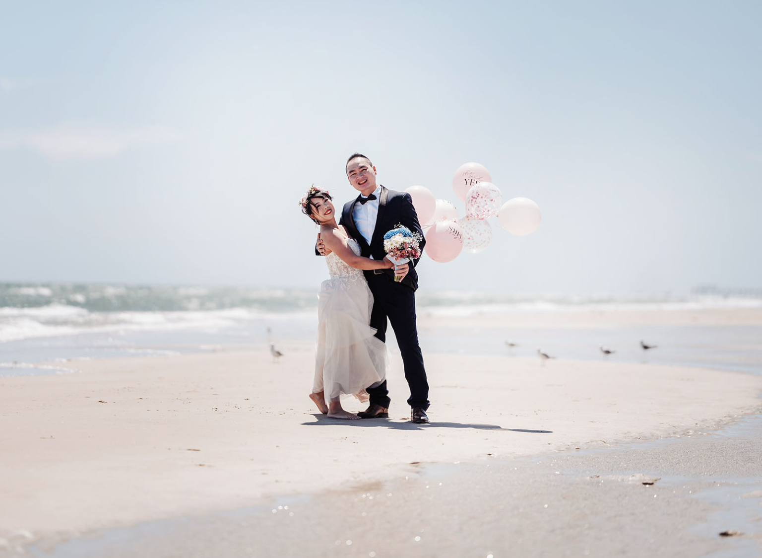bumbunga lake photoshoot - tina & eric 31 Newlyweds embrace on sunny beach with balloons and bouquet, capturing romance and joy.