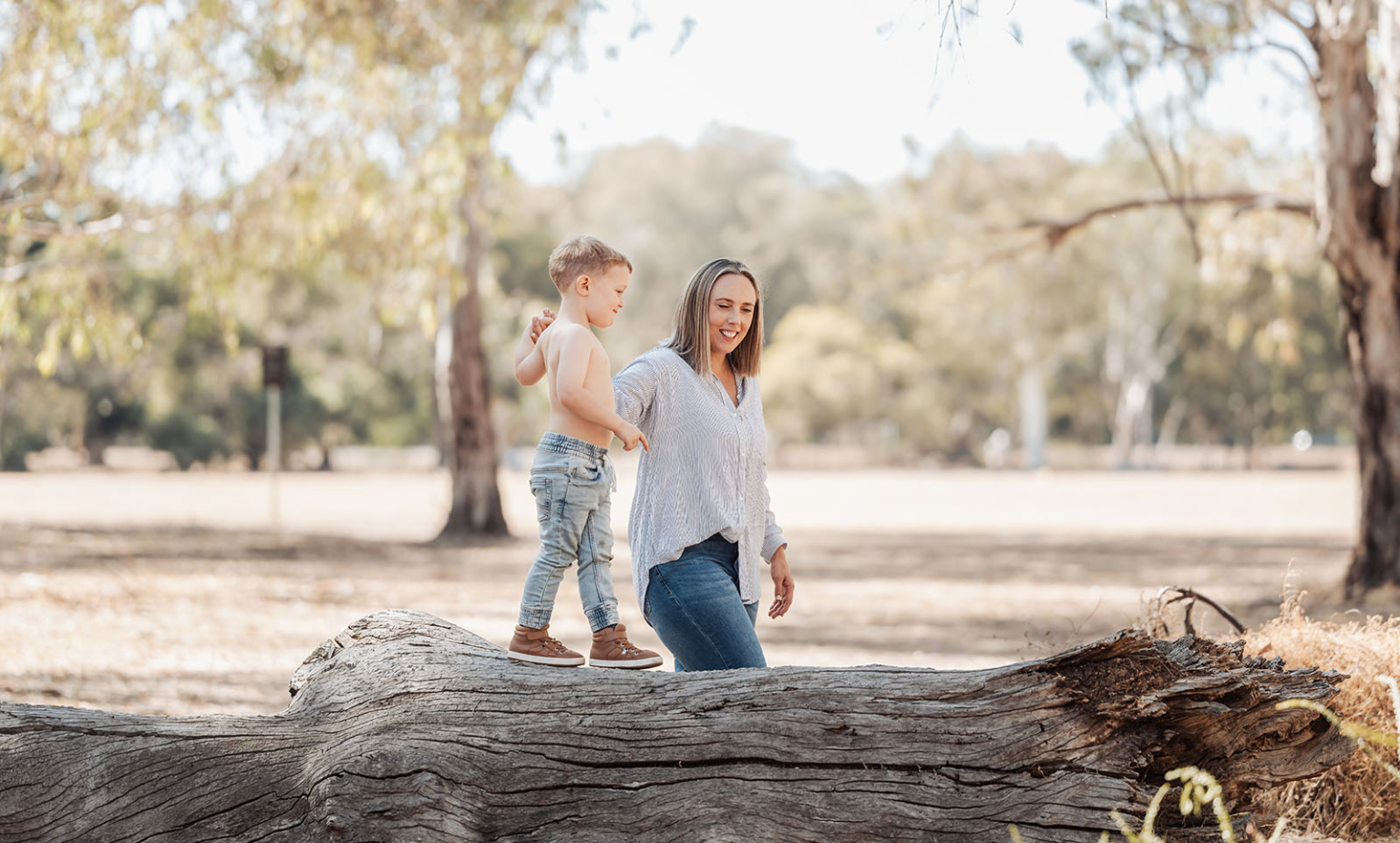 veale gardens family photography 120 Woman and child walking on fallen tree in serene woodland setting.