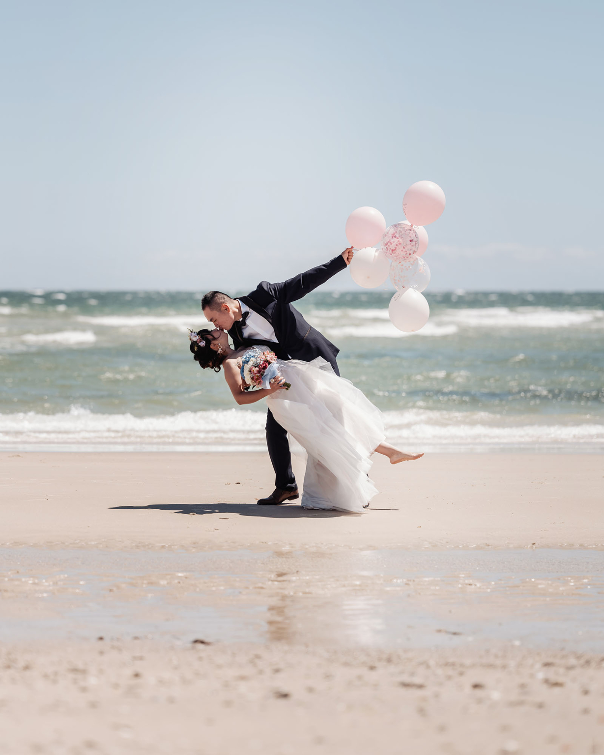 bumbunga lake photoshoot - tina & eric 28 Bride and groom embrace with balloons on a sunny beach wedding day.