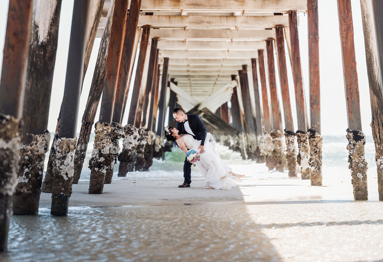 bumbunga lake photoshoot - tina & eric 41 Romantic seaside wedding kiss beneath wooden pier with elegant bride and groom.