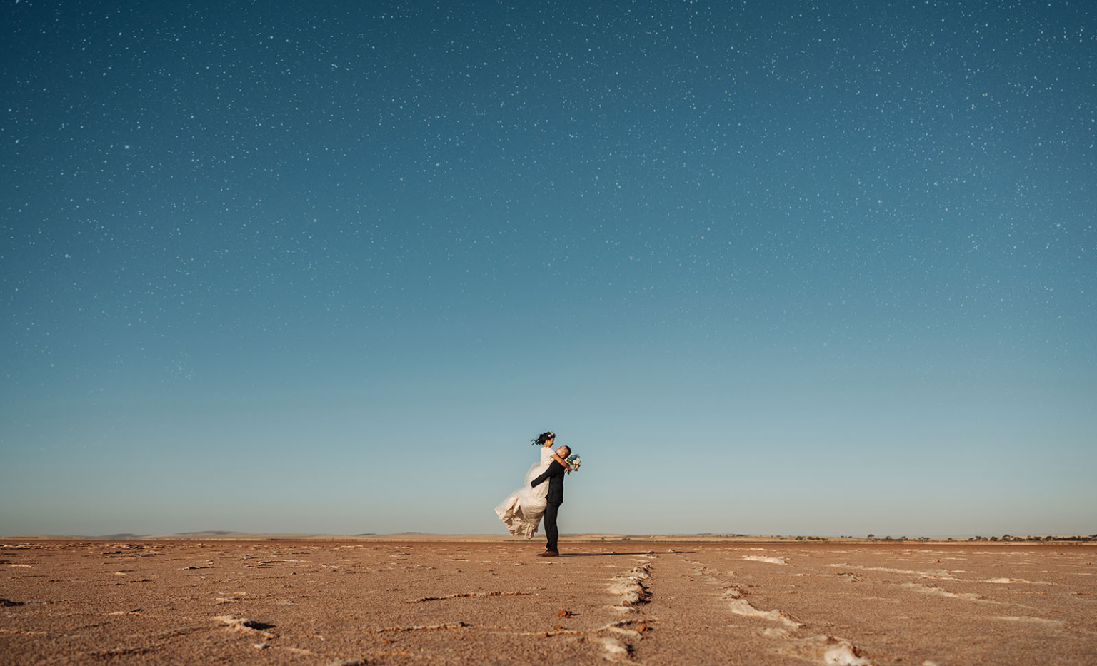 bumbunga lake photoshoot - tina & eric 74 Romantic couple embrace under starry sky in vast desert landscape.