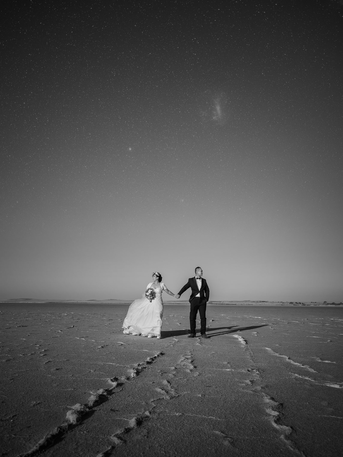 bumbunga lake photoshoot - tina & eric 75 Bride and groom in formal attire on a desert under a starry night sky.