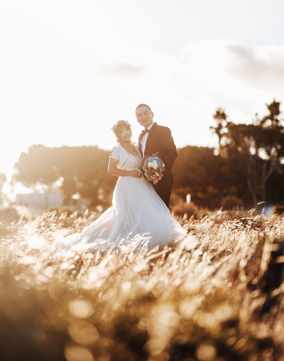 bumbunga lake photoshoot - tina & eric 85 Newlywed couple embracing in sunlit field during wedding ceremony.