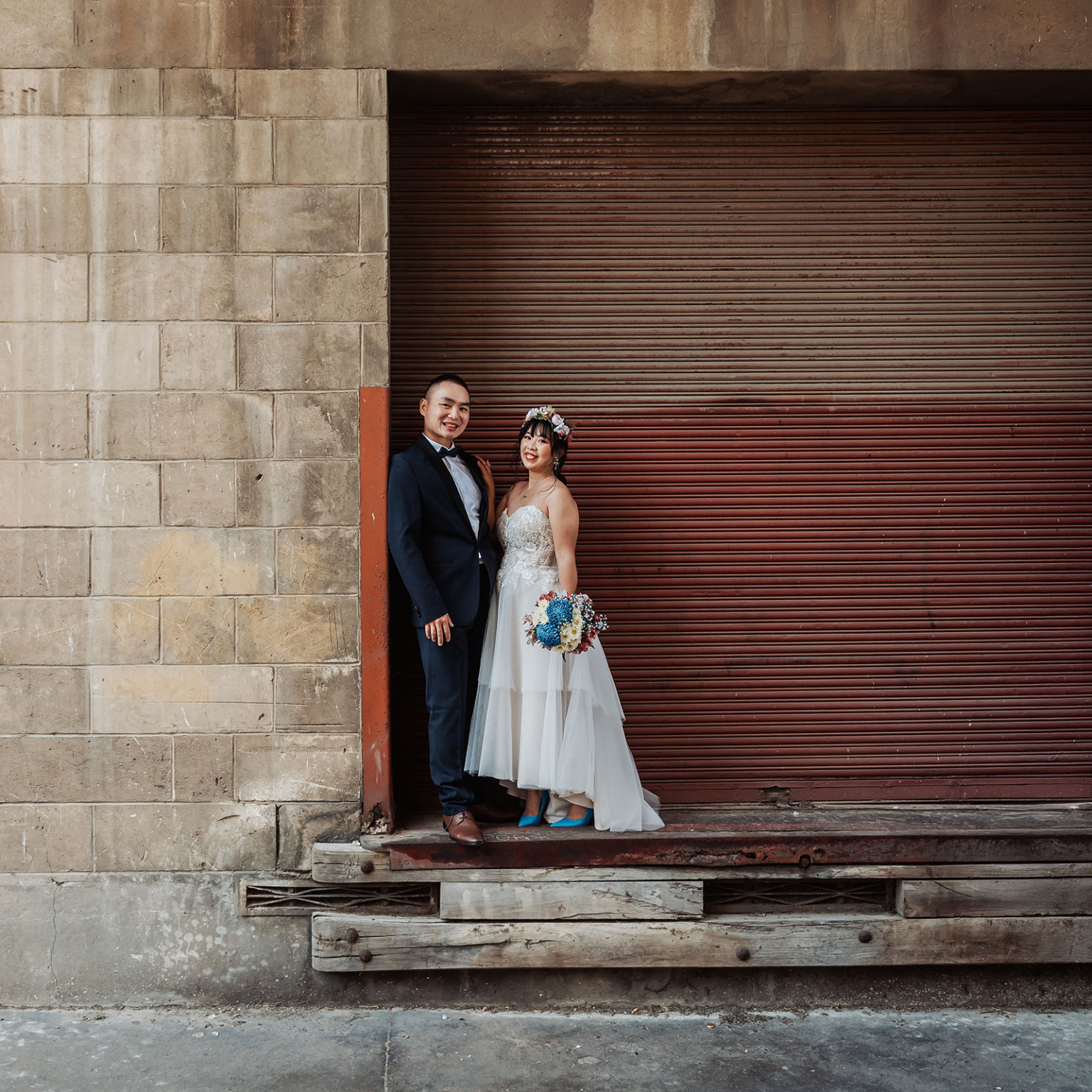 bumbunga lake photoshoot - tina & eric 53 Couple in elegant attire by a rustic building, urban wedding setting.