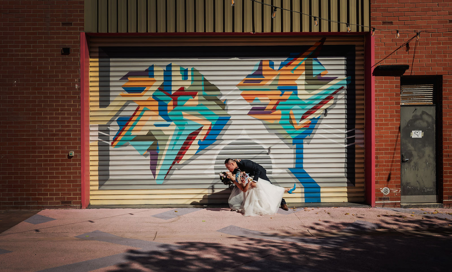 bumbunga lake photoshoot - tina & eric 61 Urban wedding couple posed before colorful mural in vibrant city setting.
