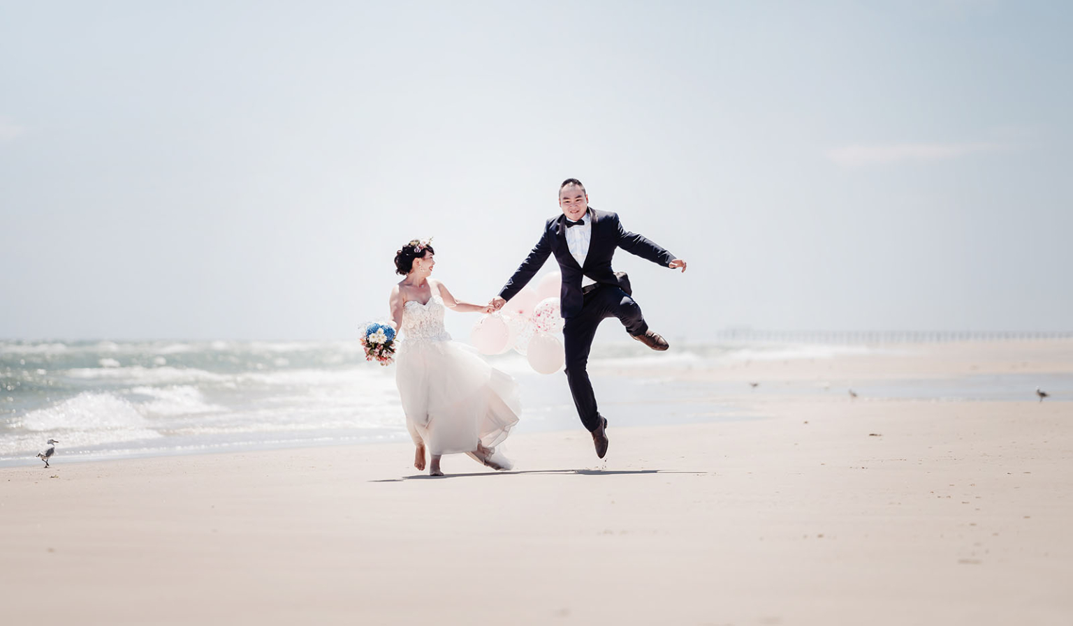 bumbunga lake photoshoot - tina & eric 33 Bride and groom celebrate wedding joyfully on beach with ocean backdrop.