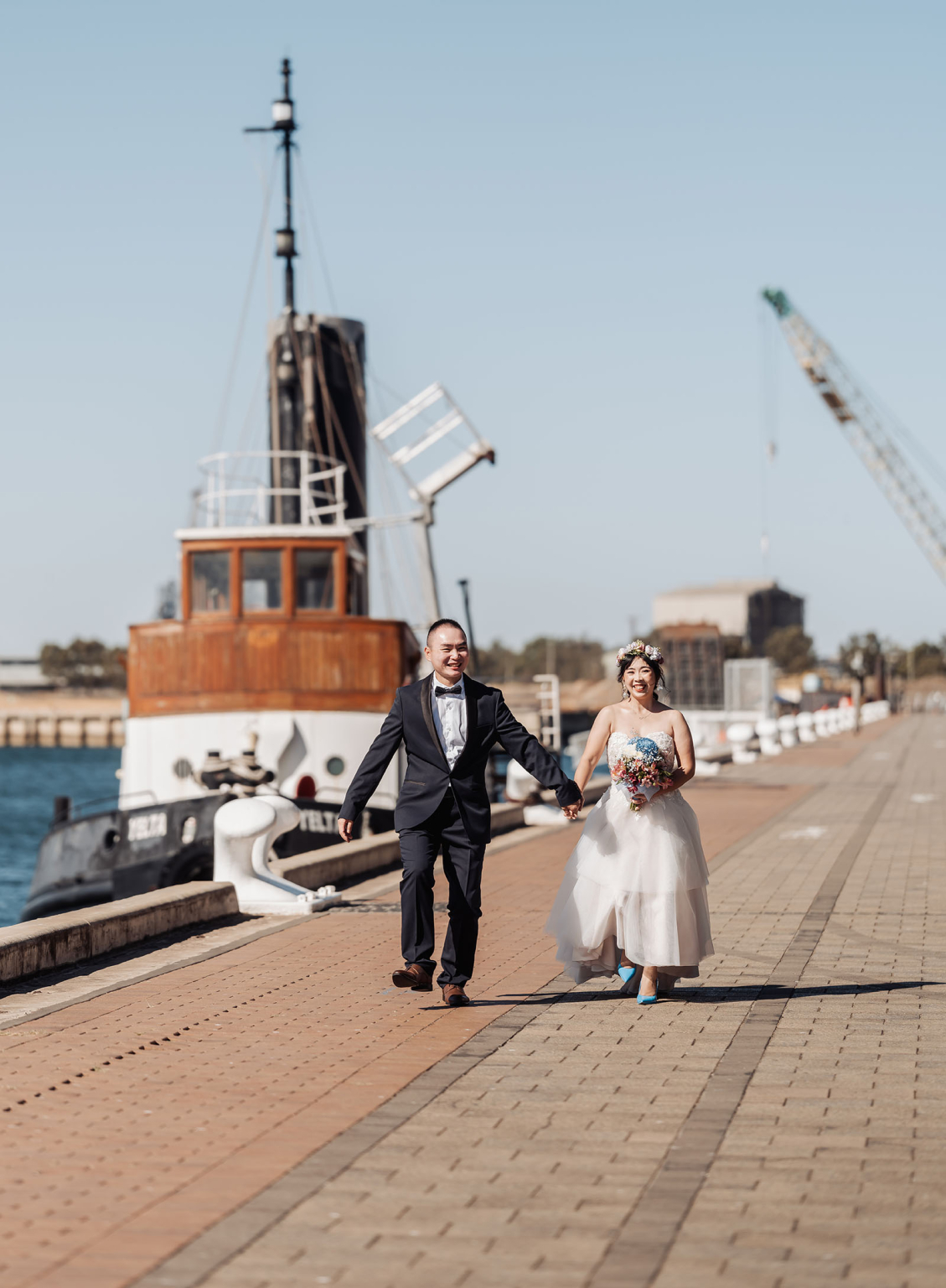 bumbunga lake photoshoot - tina & eric 64 Wedding couple walking on waterfront promenade with ship and urban background.