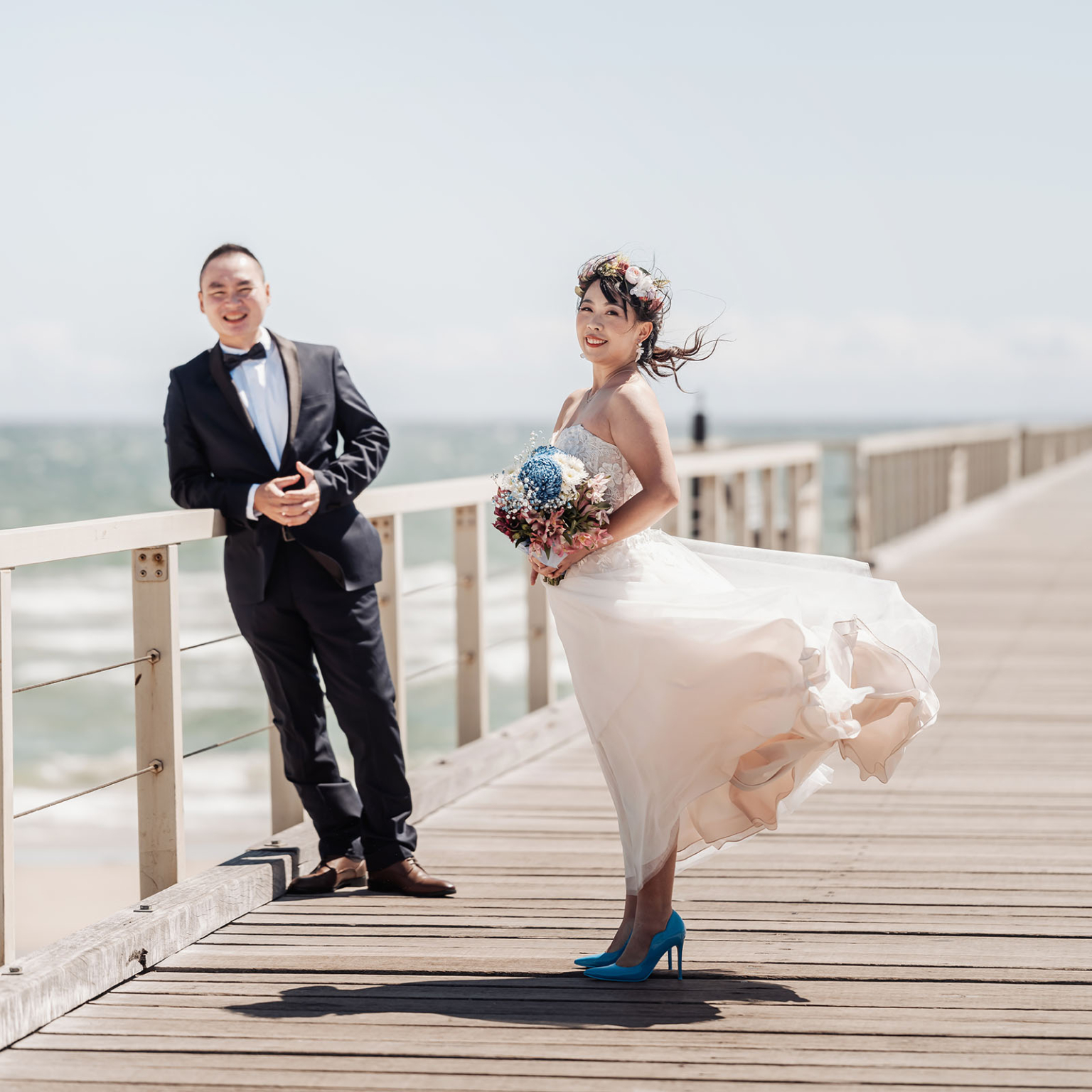 bumbunga lake photoshoot - tina & eric 43 Romantic seaside wedding couple posing on a boardwalk under clear blue sky.