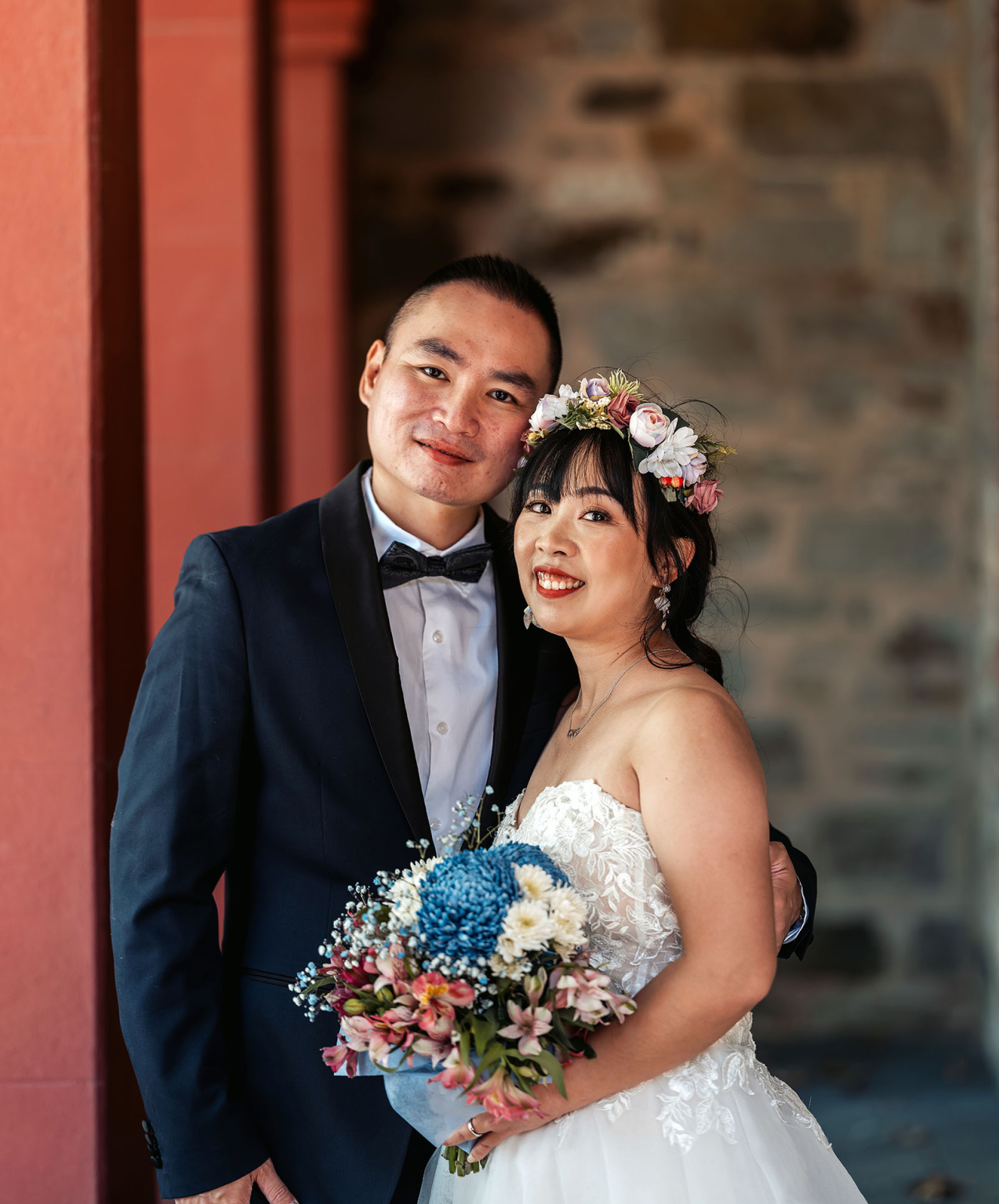 bumbunga lake photoshoot - tina & eric 58 Bride and groom share joyful moment on wedding day with colorful flowers and stone backdrop.
