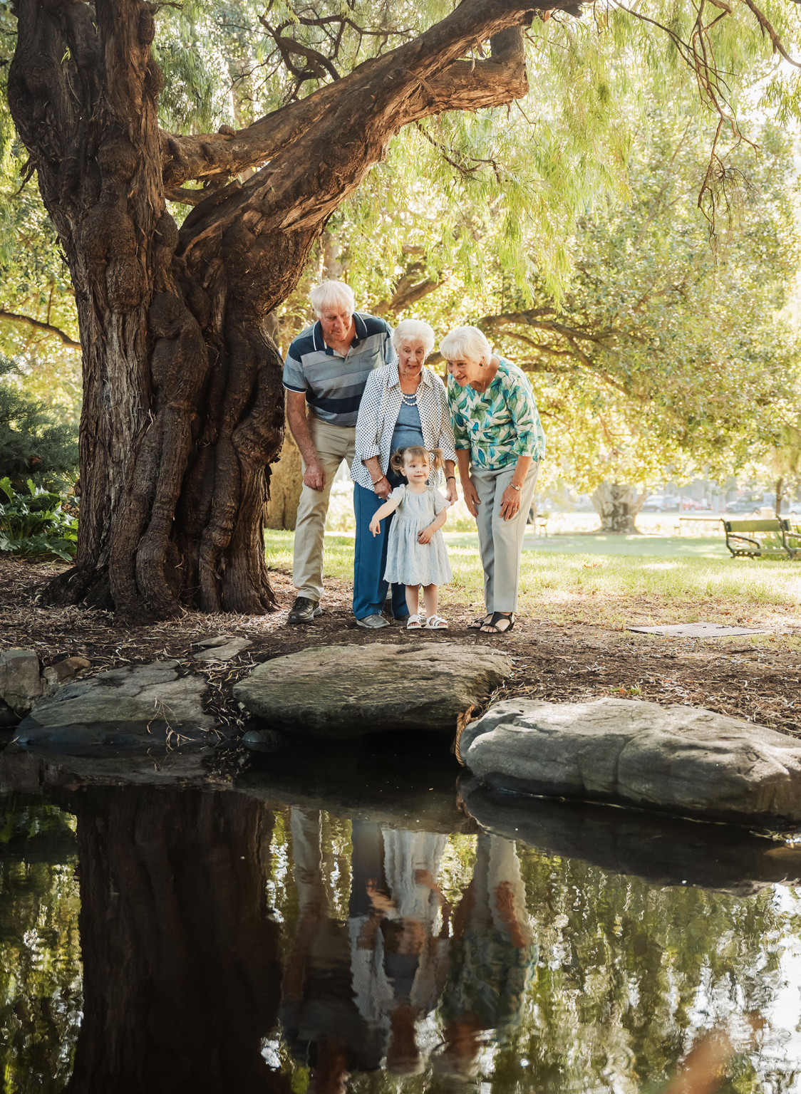 veale gardens family photoshoot 6 Elderly trio and child explore pond in lush green park.