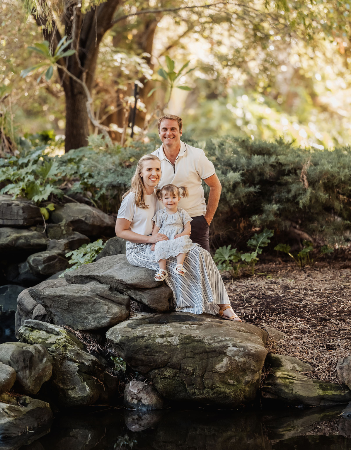 veale gardens family photoshoot 7 Family enjoying nature on moss-covered rocks in a lush forest.