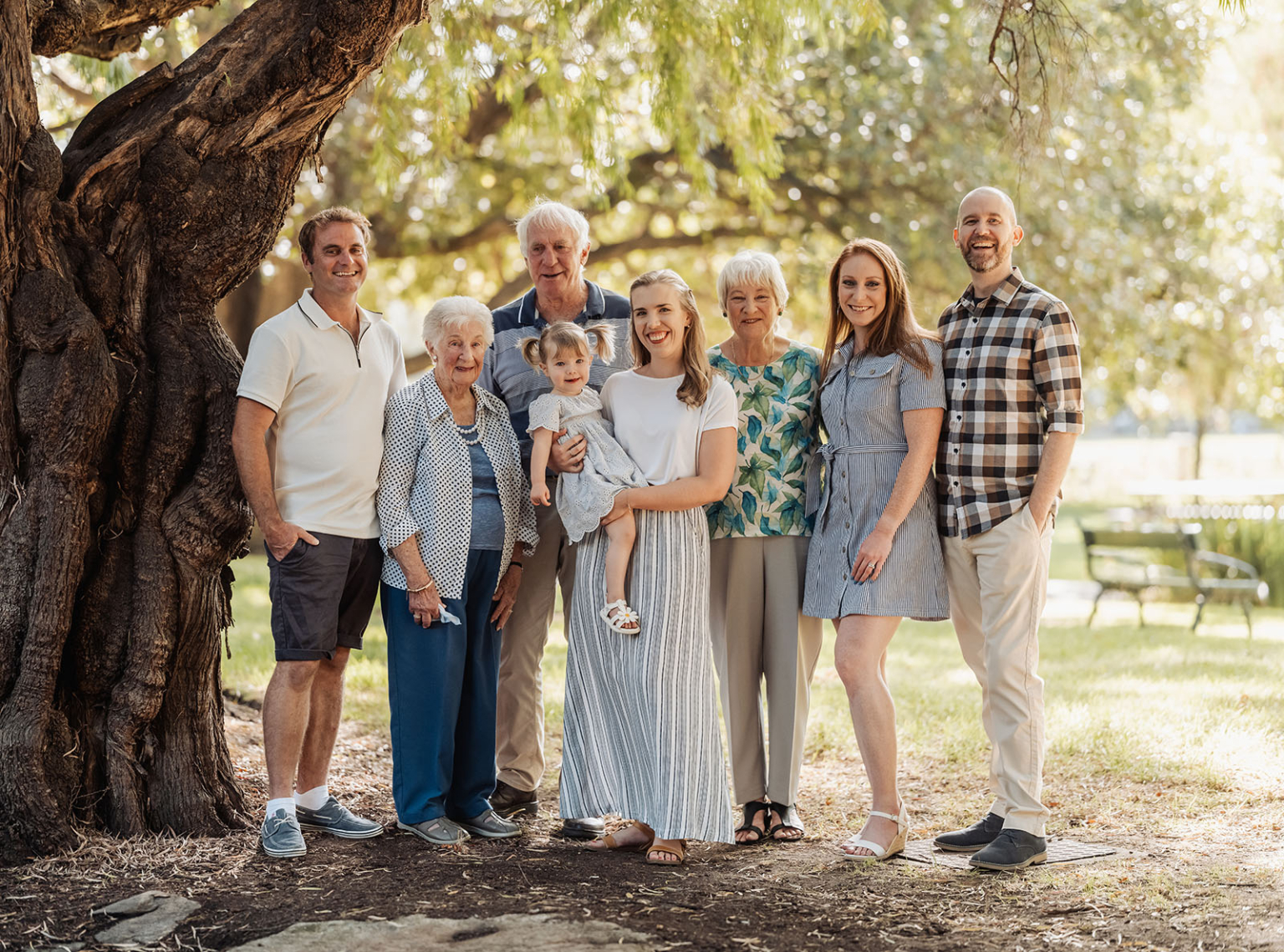 veale gardens family photoshoot 5 Family gathering under tree in park, enjoying nature and sunshine.