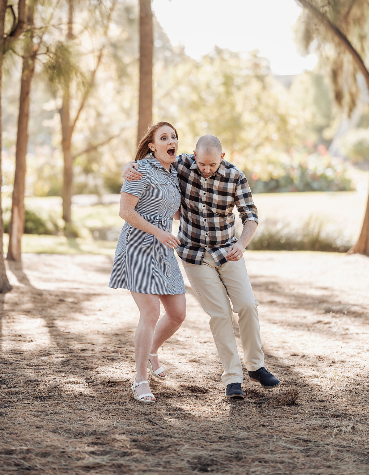 veale gardens family photoshoot 15 Happy couple laughing and walking quickly through a sunlit, lush park.
