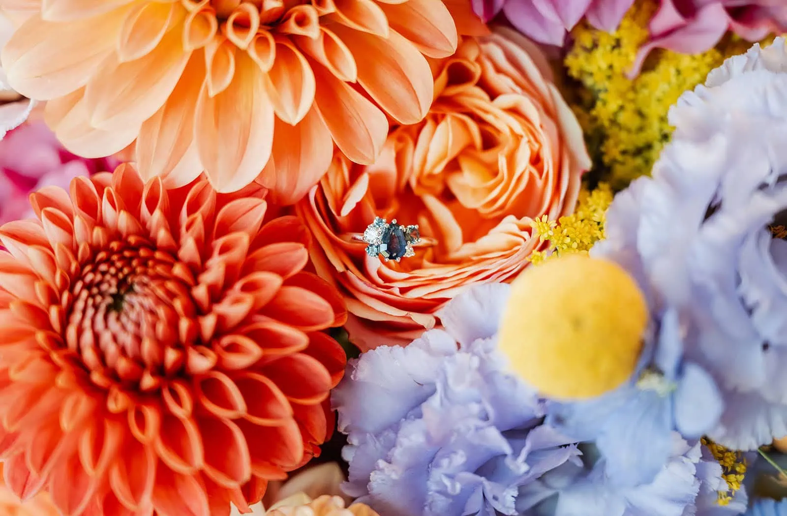 engagement rings under $2,000: 7 designs that don't look cheap 4 Bouquet with orange flowers, purple lisianthus, and ring featuring sapphire and diamonds.