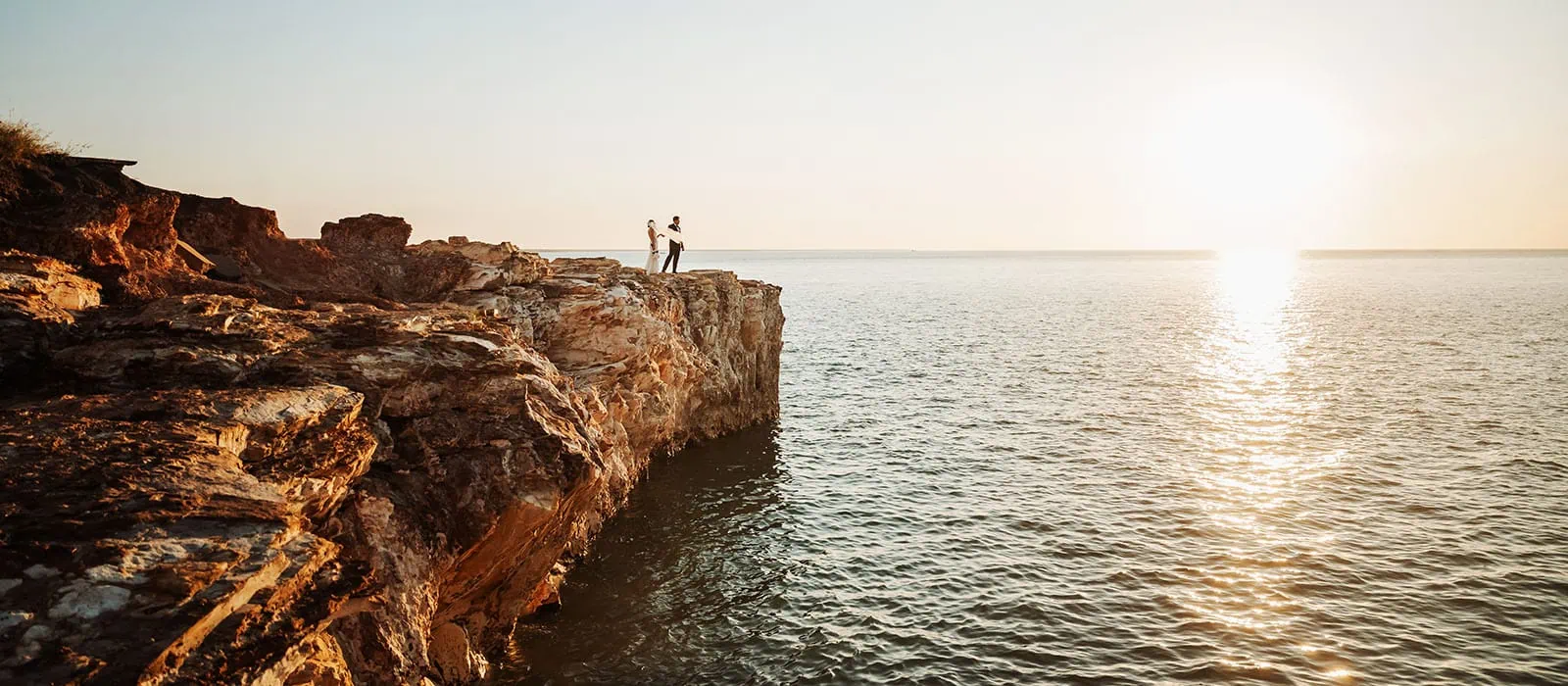 darwin wedding photography - wedding photographers & video 16 Coastal cliff sunset with silhouettes, ocean view, and sun reflections.