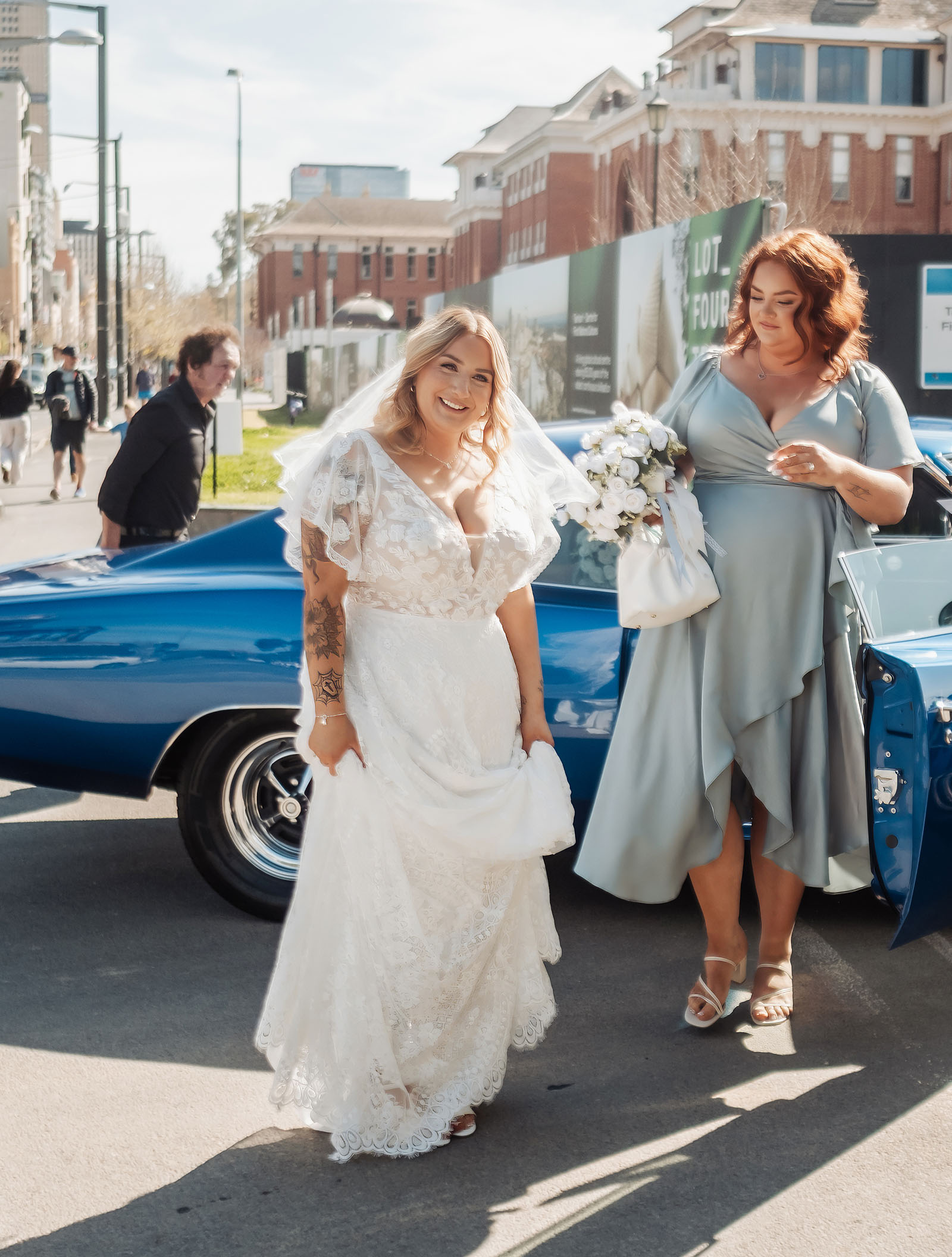 botanic gardens adelaide wedding - melanie & adrian 220 Bride and bridesmaid pose beside elegant vintage car on wedding day.