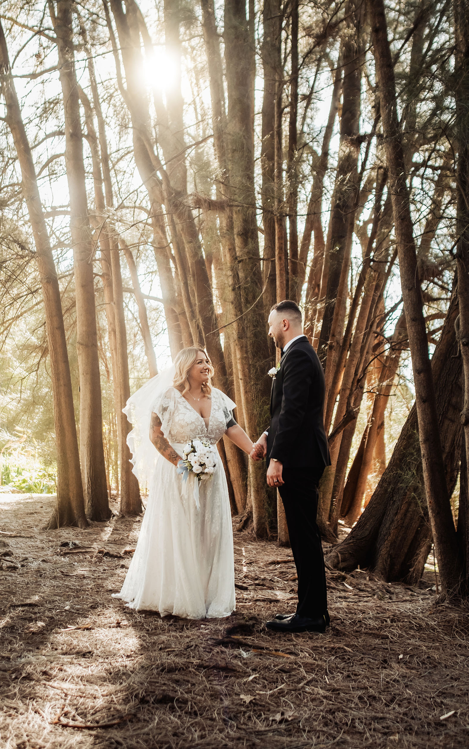 botanic gardens adelaide wedding - melanie & adrian 244 Enchanting forest wedding ceremony with bride and groom under tall trees.
