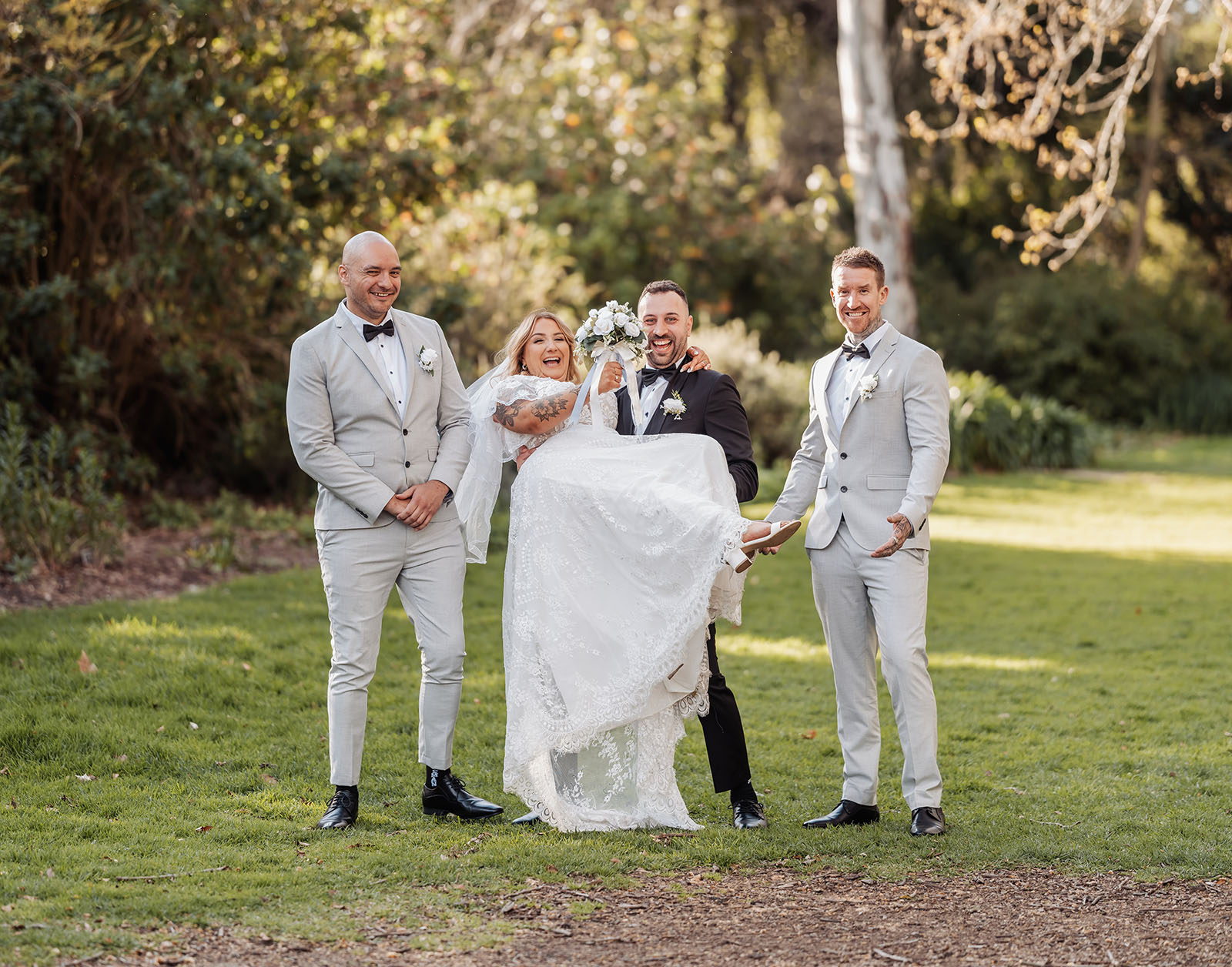 botanic gardens adelaide wedding - melanie & adrian 255 Bride and groom celebrating wedding with joyful guests at outdoor reception.