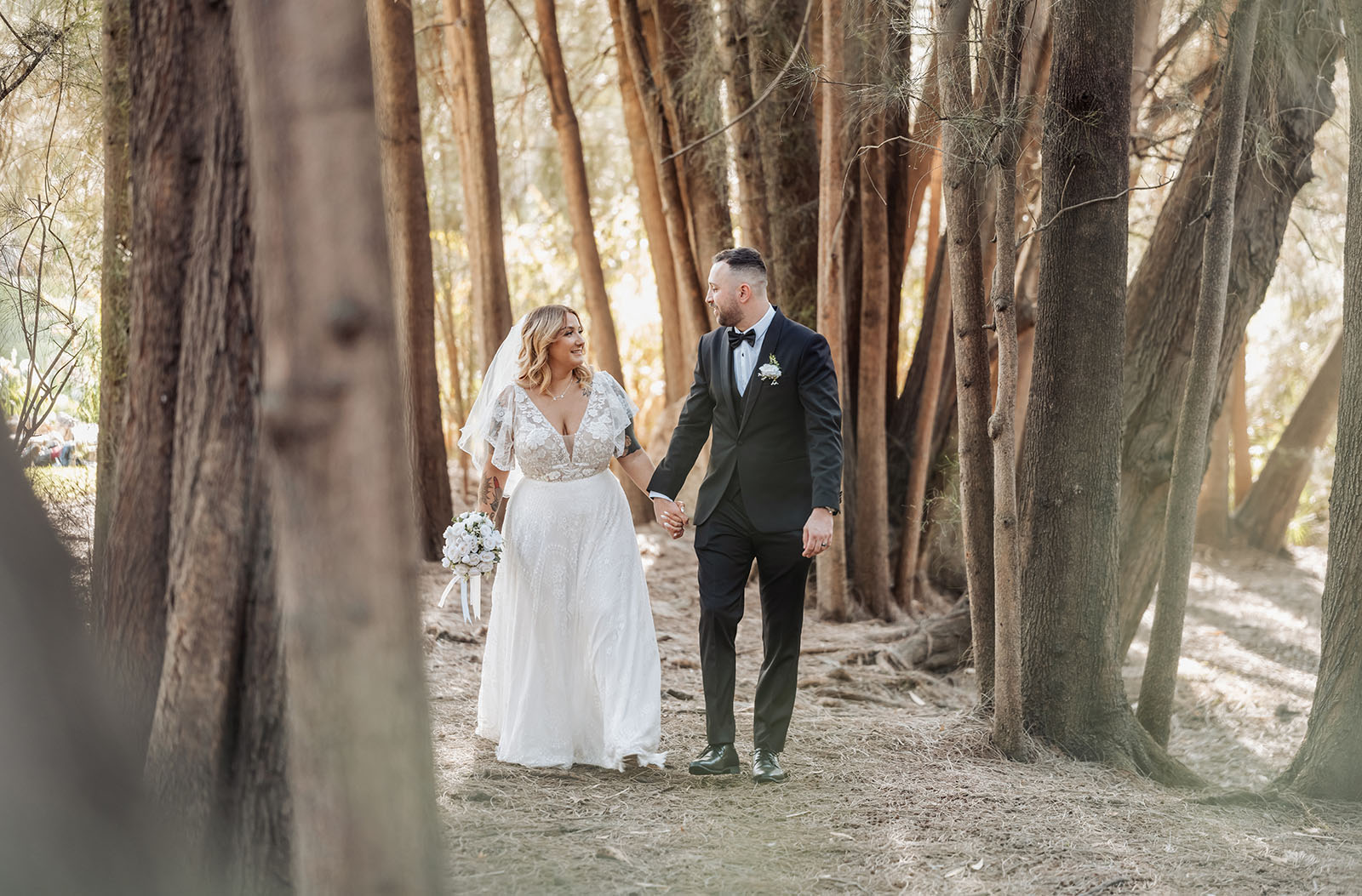 botanic gardens adelaide wedding - melanie & adrian 245 Newlywed couple walking in a serene forest trail, surrounded by lush greenery.