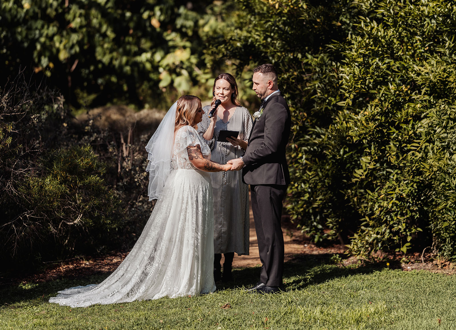botanic gardens adelaide wedding - melanie & adrian 228 Elegant outdoor wedding ceremony with floral decorations and aisle chairs under a sunny sky.
