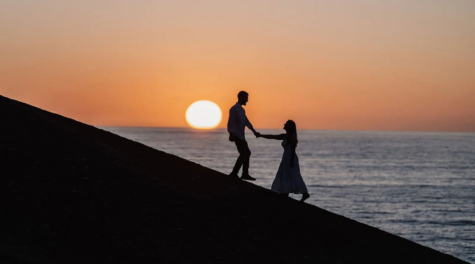 how to find affordable wedding venues during peak season 32 Silhouetted couple at sunset by the ocean, sharing a moment of connection and tranquility.