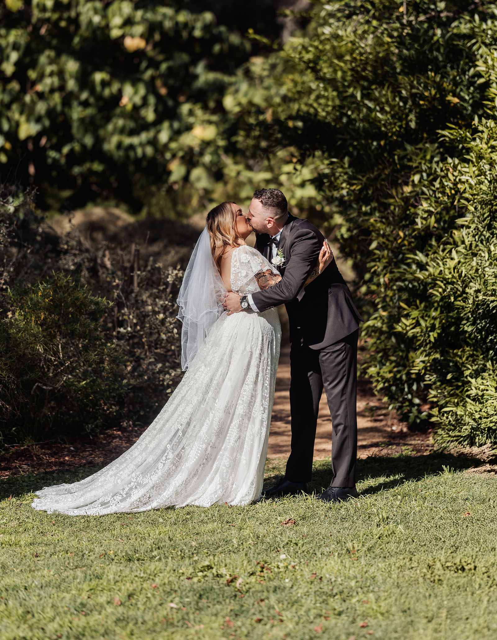 botanic gardens adelaide wedding - melanie & adrian 230 Bride and groom share a kiss in a lush garden.