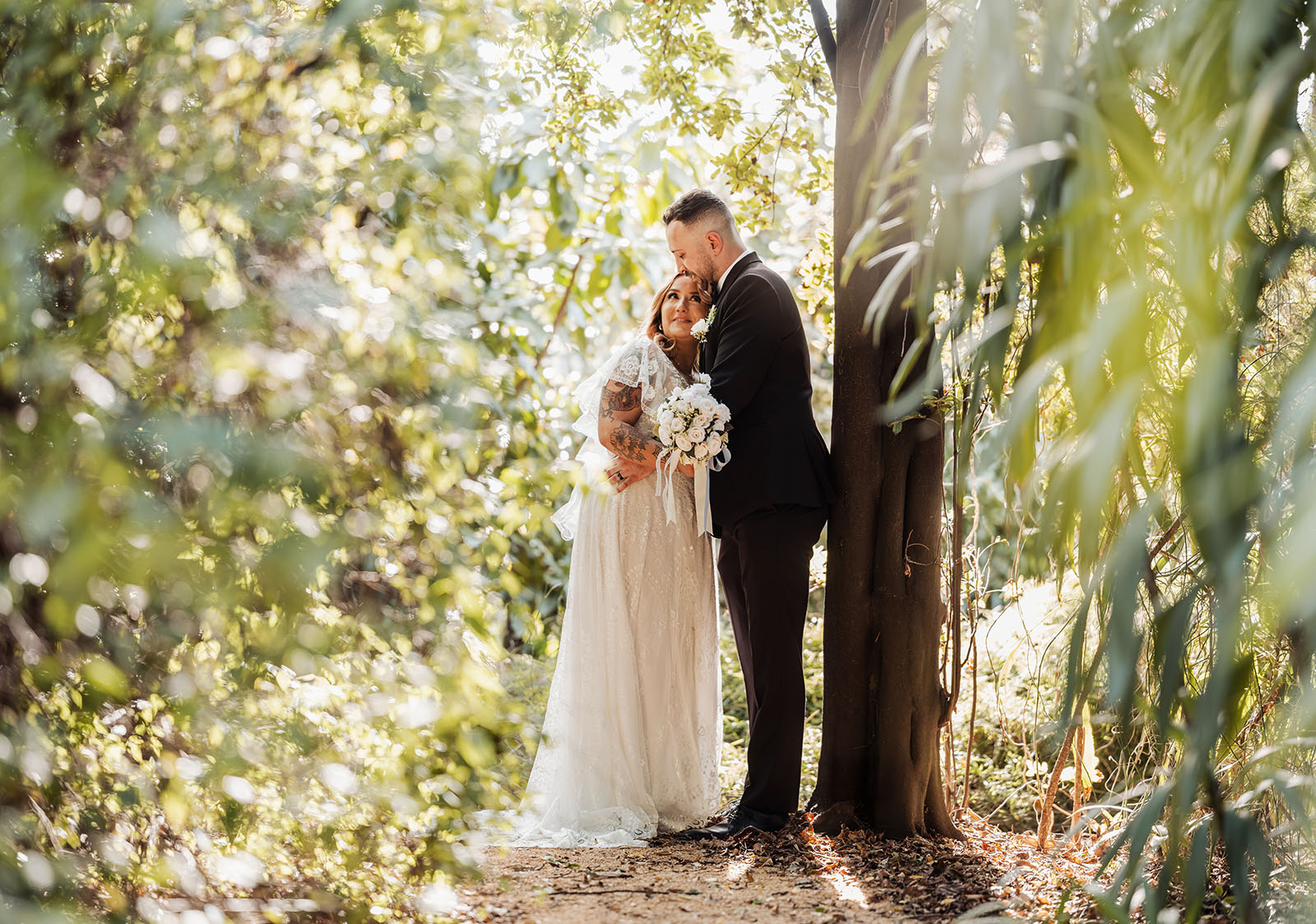 botanic gardens adelaide wedding - melanie & adrian 237 Bride and groom embracing in scenic outdoor landscape, celebrating love.