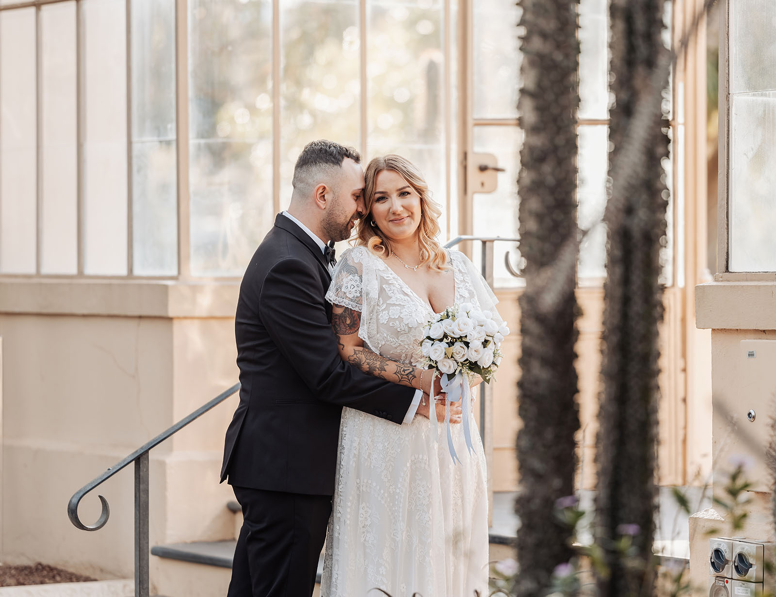 botanic gardens adelaide wedding - melanie & adrian 253 Elegant couple embracing on their wedding day against a scenic outdoor backdrop.