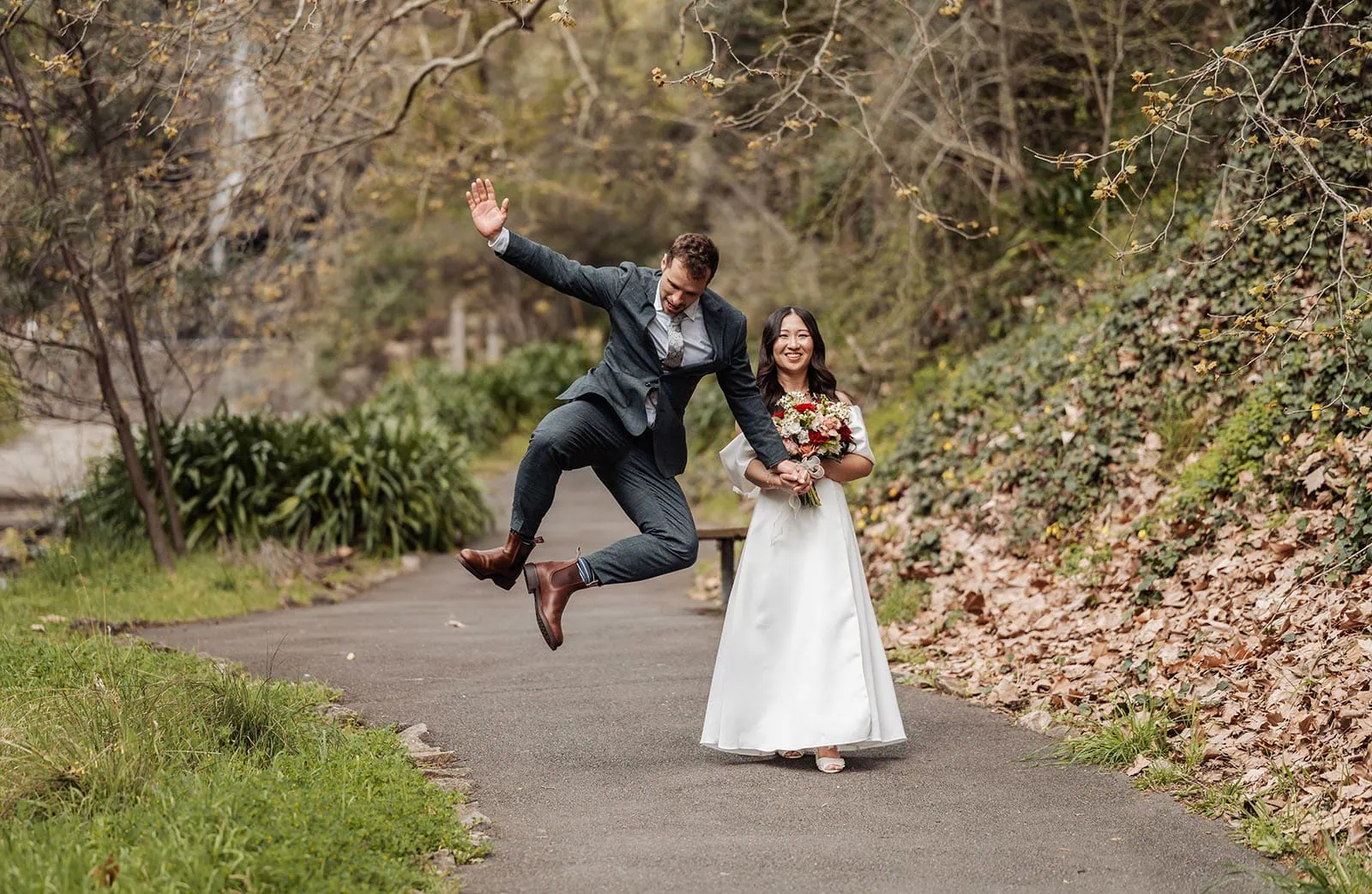 utopia waterfall gully wedding - sally & ben 233 Joyful bride jumping in wedding gown, celebrating happiness and love.