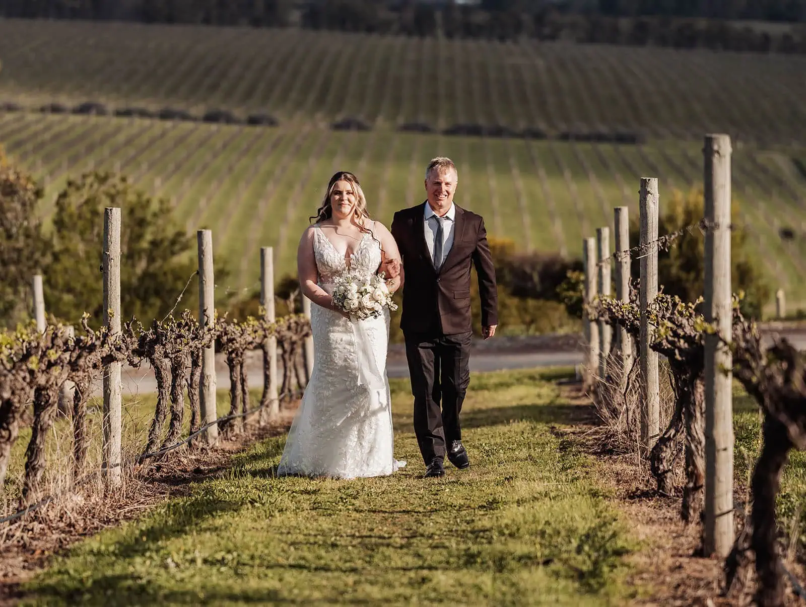 beach rd wines wedding - hana & jessie 55 Bride and father walking through vineyard on wedding day.