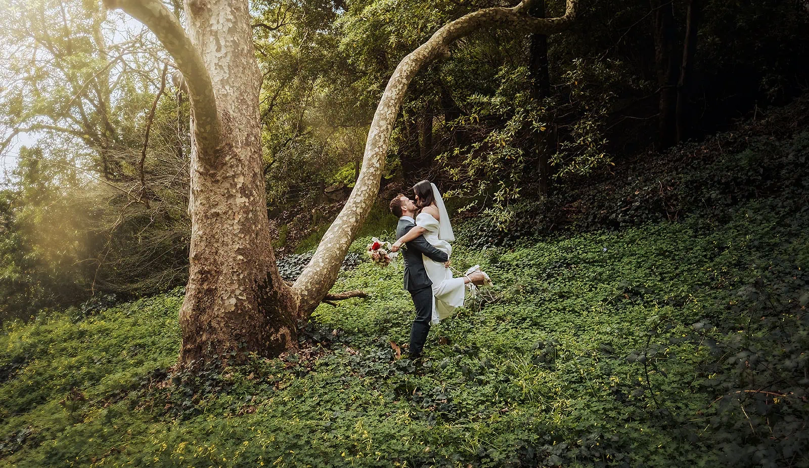 utopia waterfall gully wedding - sally & ben 243 Bride and groom pose amidst lush greenery in a romantic outdoor setting.
