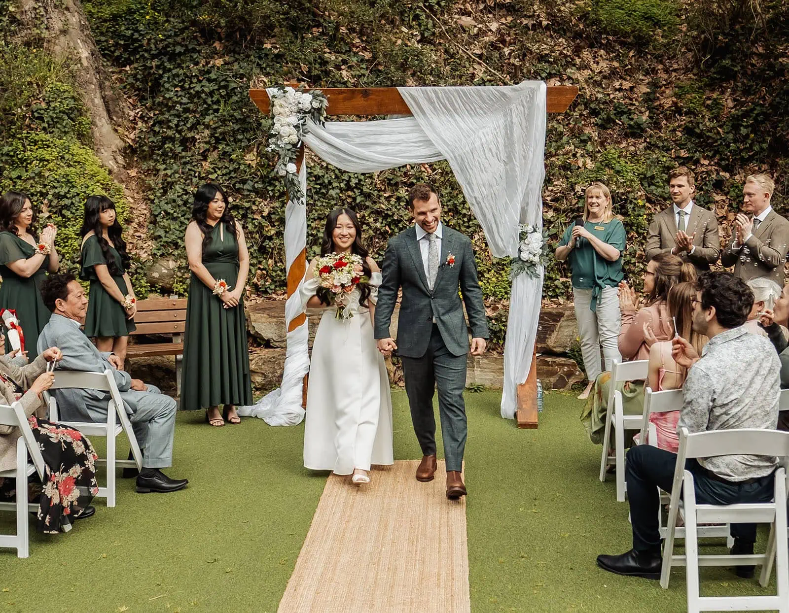 utopia waterfall gully wedding - sally & ben 229 Bride and groom walking down the wedding aisle, surrounded by flowers and guests.