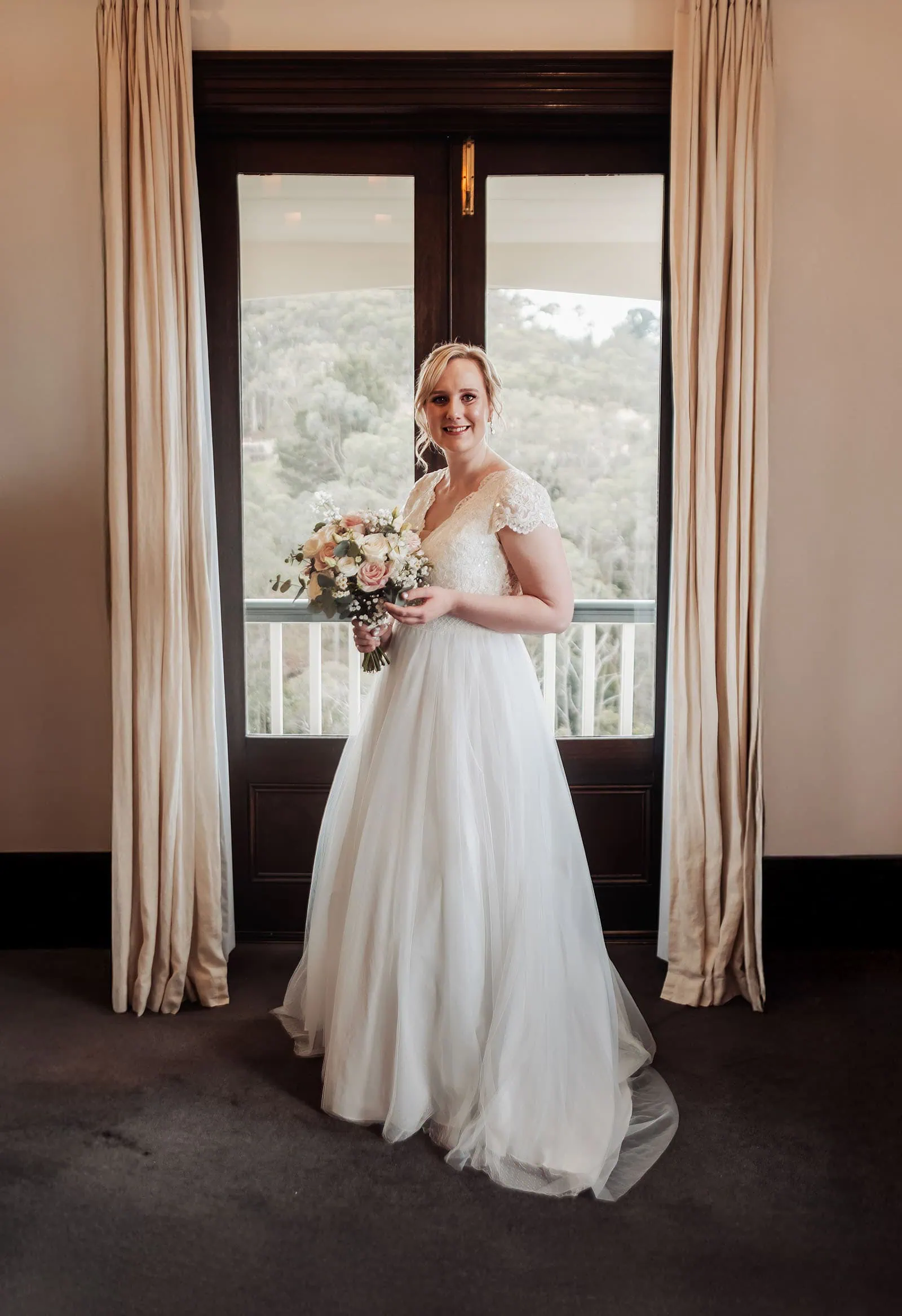 mt lofty house elopement - kimberley & michael 172 Bride in wedding dress gazing out window, sunlight illuminating her silhouette.