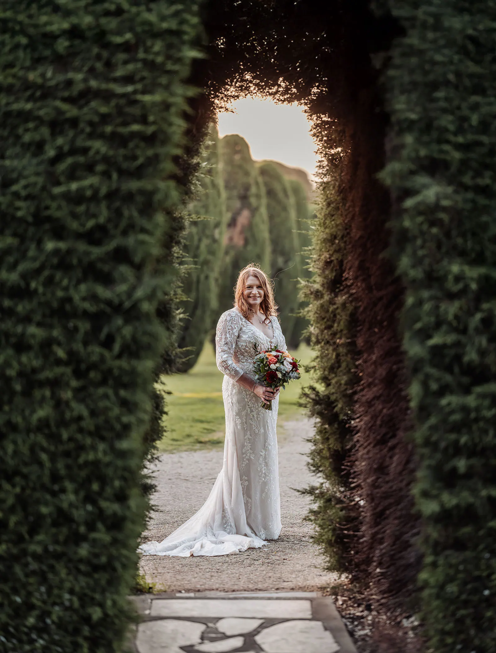 carrick hill wedding - jo & david 308 Bride standing under floral garden archway in elegant wedding dress.