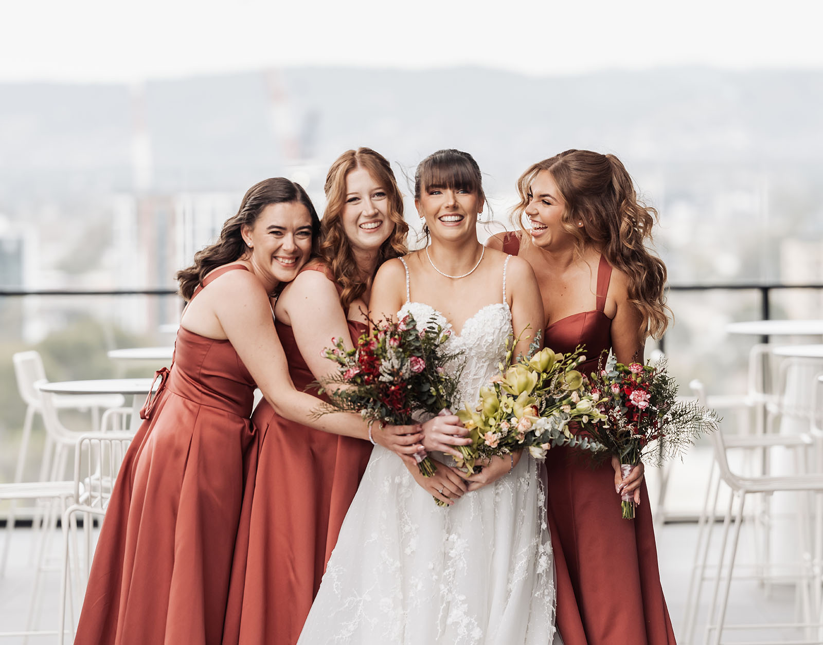 adelaide botanic gardens summerhouse wedding - belinda & ian 155 Bride and bridesmaids celebrate on a scenic rooftop.