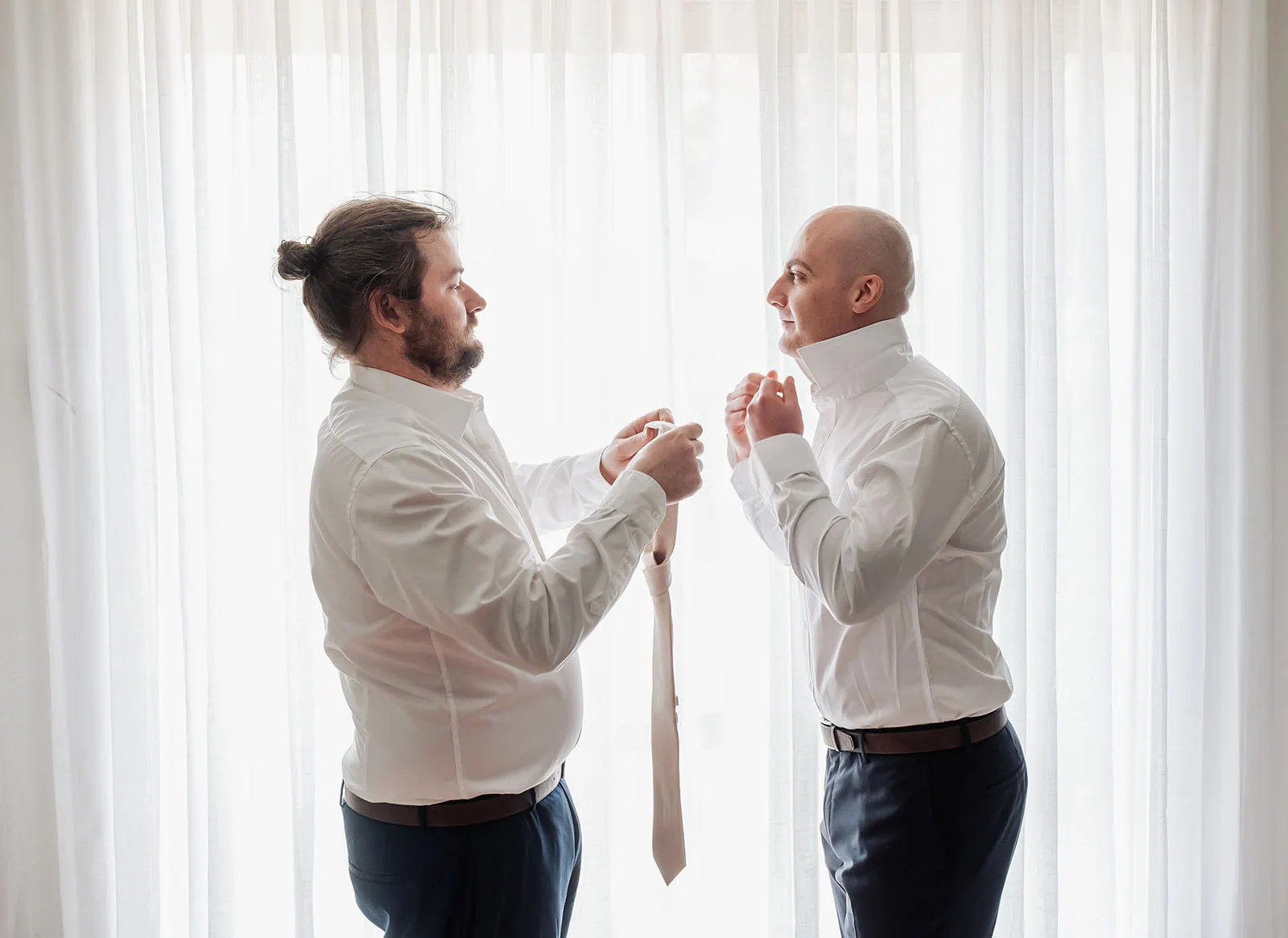 grand cru estate wedding - isabella & nick 96 Two men laughing outdoors in casual attire, enjoying a candid moment.