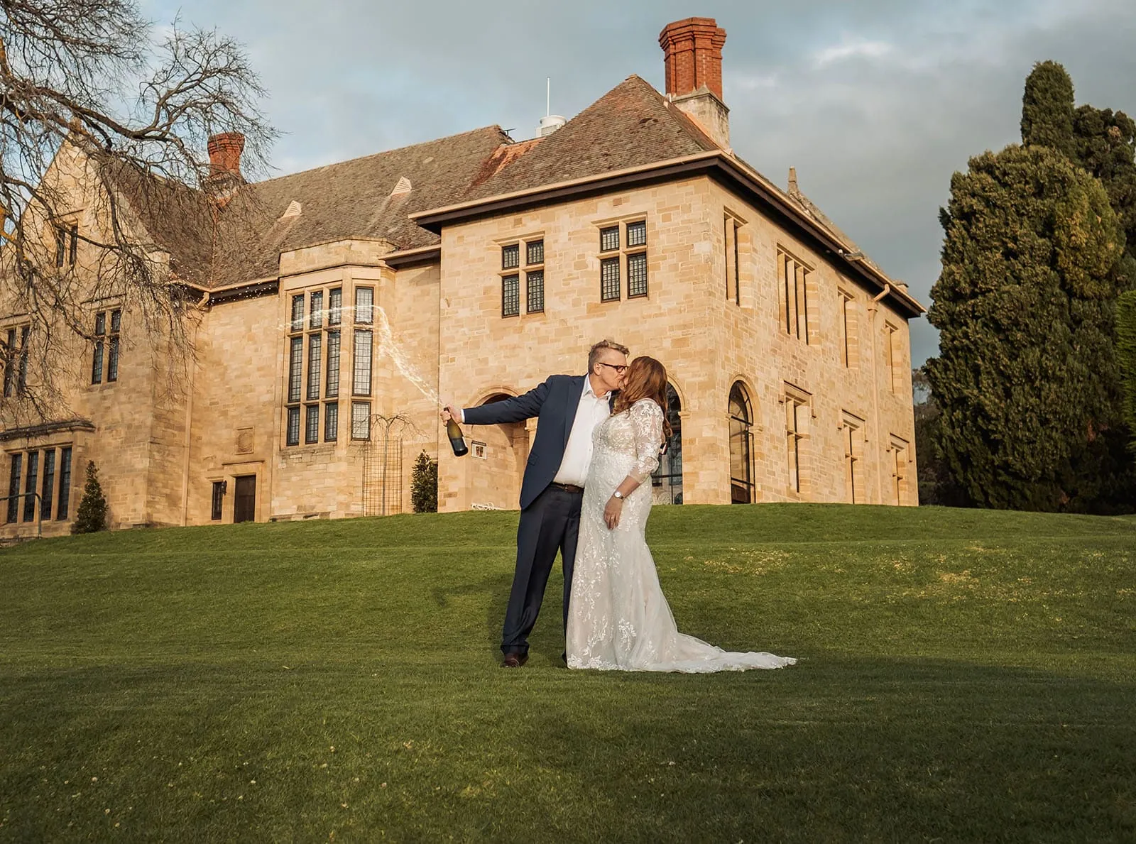 carrick hill wedding - jo & david 314 Elegant couple celebrating on a grand estate lawn amidst picturesque scenery.