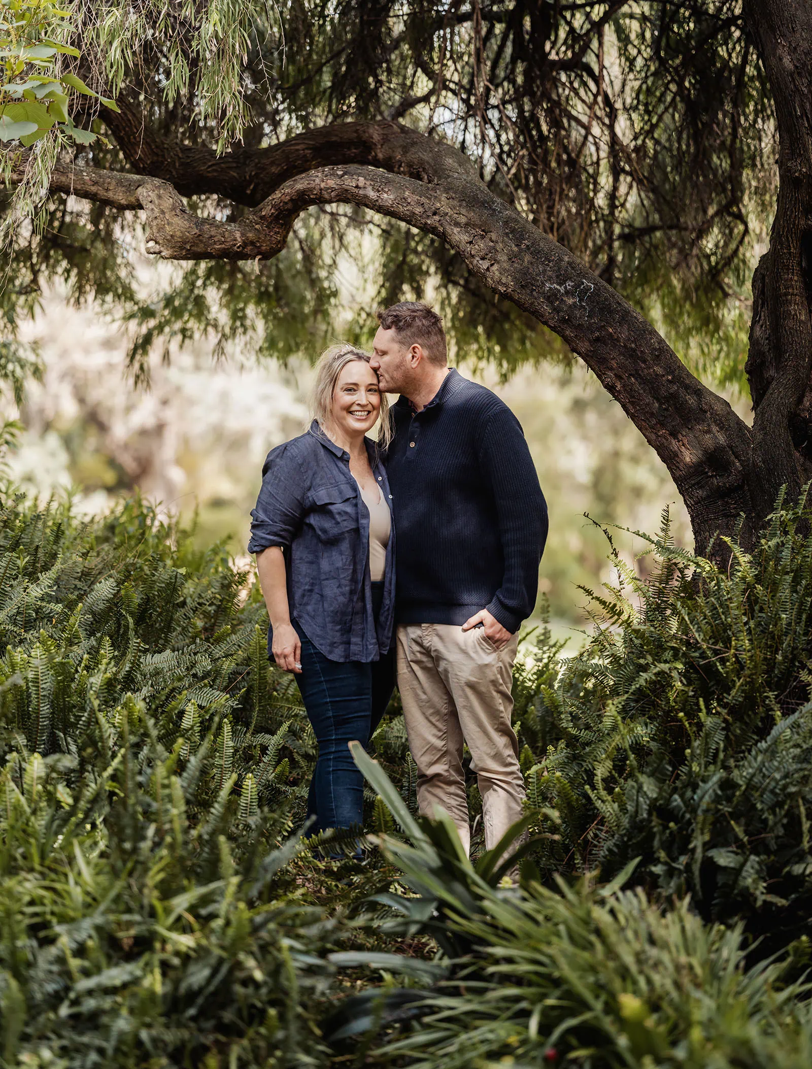 southern parklands family photography 34 Couple embracing in a serene forest moment, surrounded by lush greenery.