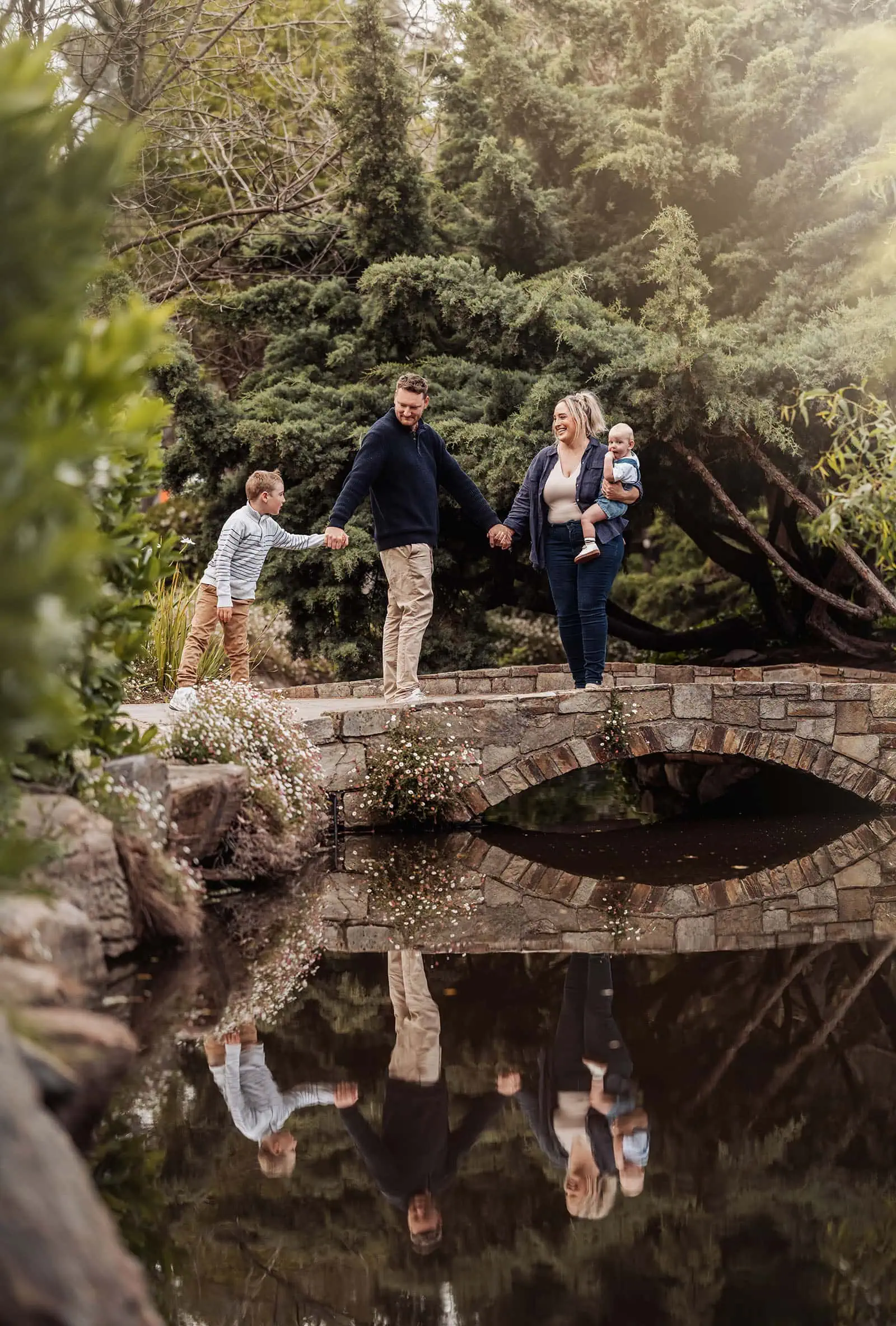 southern parklands family photography 26 Family walking on a scenic bridge, enjoying nature and leisure time together.