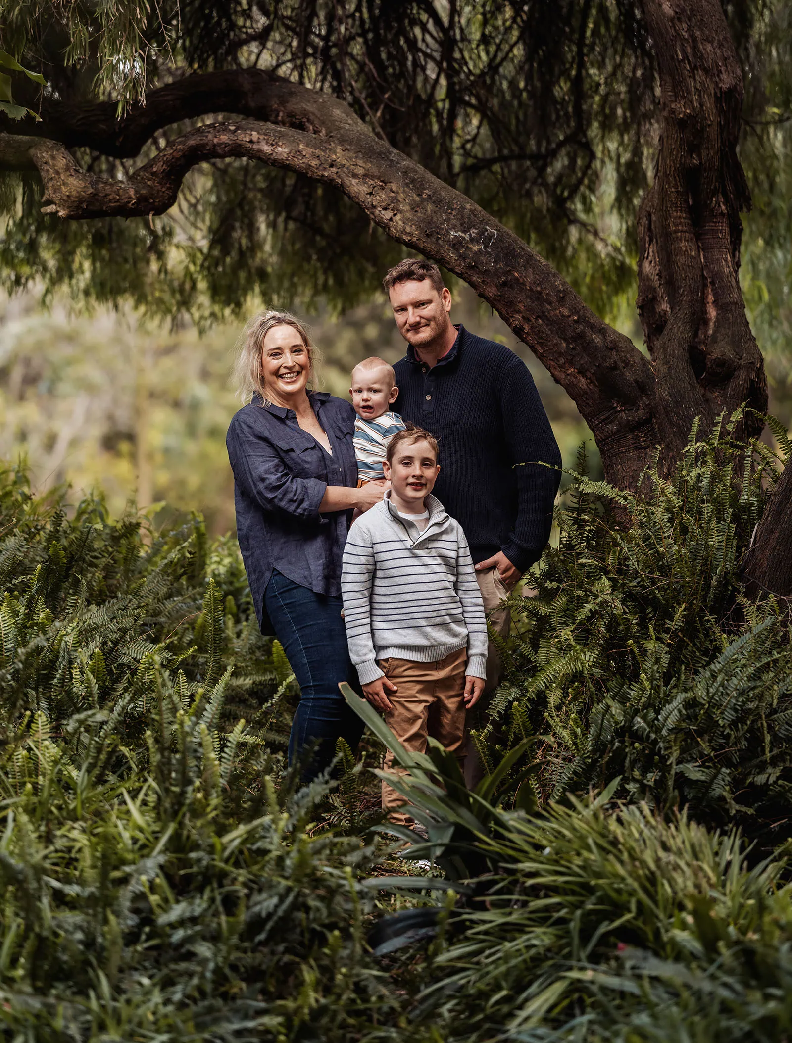 southern parklands family photography 33 Family enjoying a peaceful walk in a lush, green forest.
