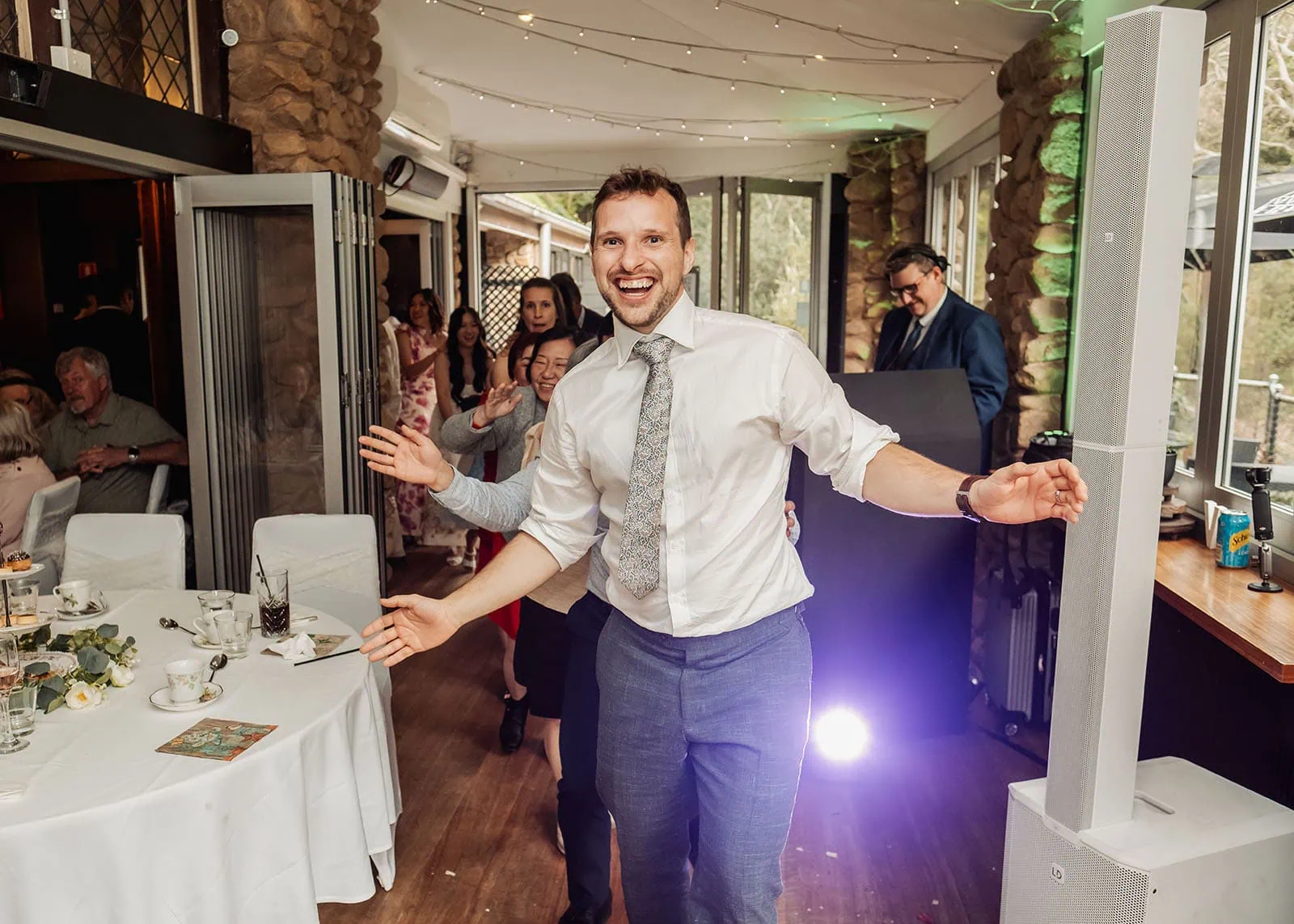 utopia waterfall gully wedding - sally & ben 268 Festive conga line at a party with colorful lights and joyful dancers.