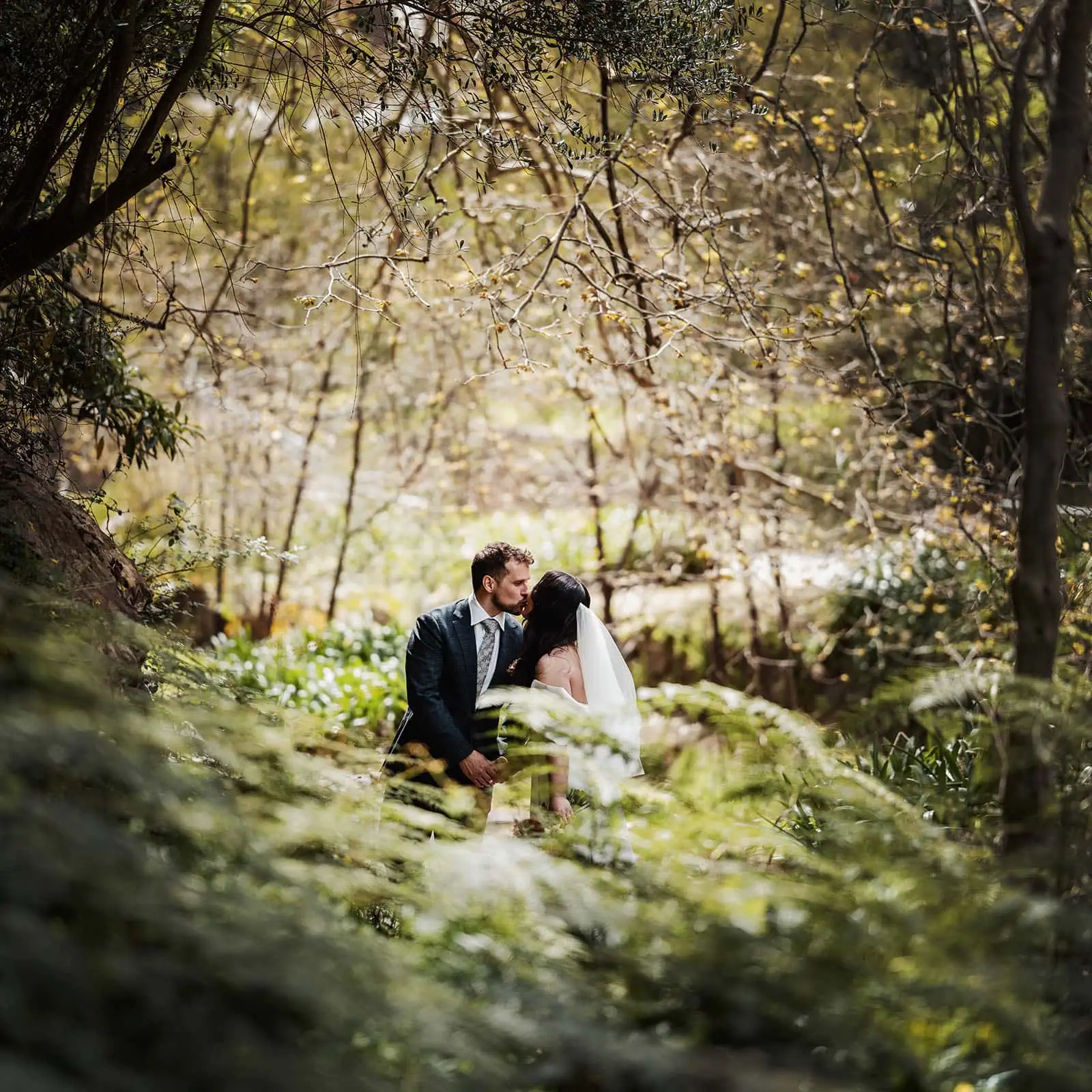 utopia waterfall gully wedding - sally & ben 239 Romantic forest wedding couple sharing a kiss amid nature.