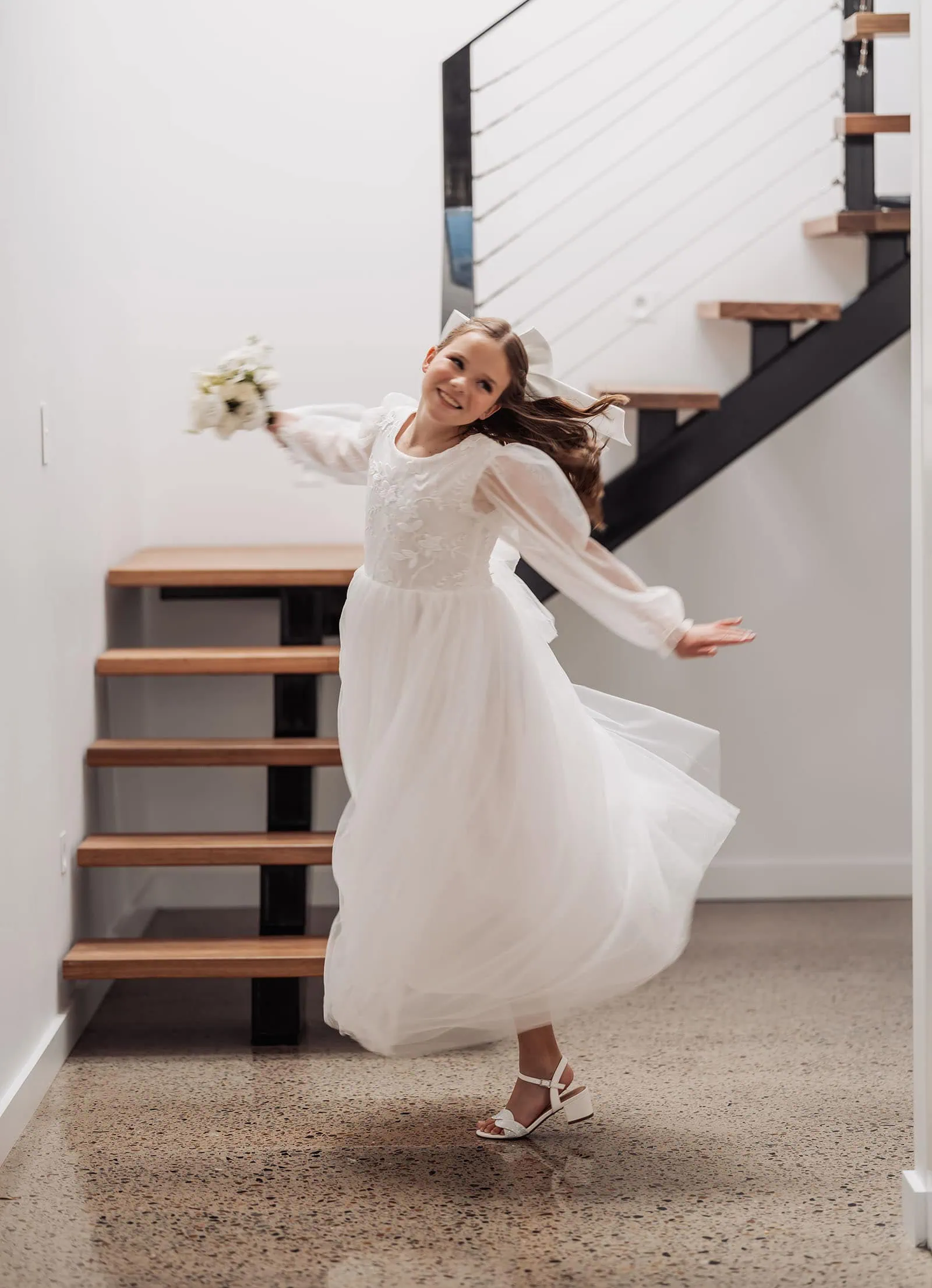 beach rd wines wedding - hana & jessie 43 Girl spinning joyfully in a bright hallway.