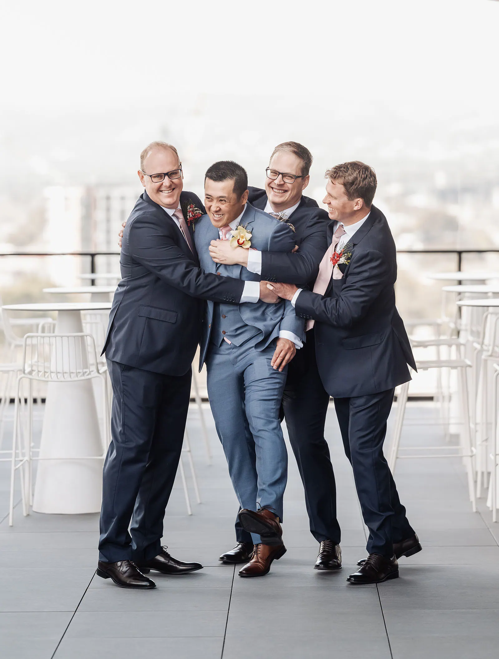 adelaide botanic gardens summerhouse wedding - belinda & ian 134 Groom and groomsmen celebrating on a rooftop with city skyline backdrop.