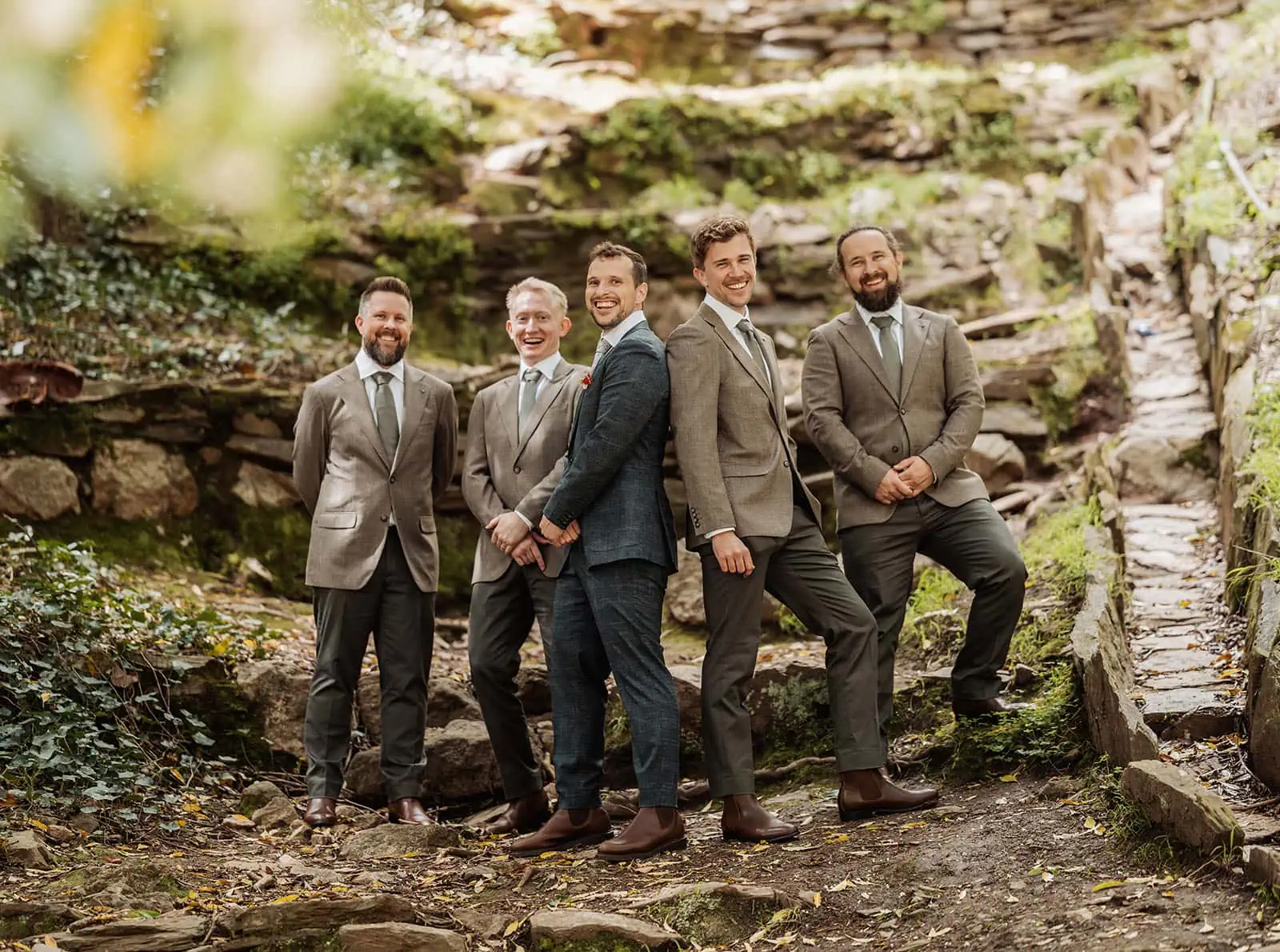 utopia waterfall gully wedding - sally & ben 245 Groom smiling with groomsmen in formal attire at a wedding celebration.