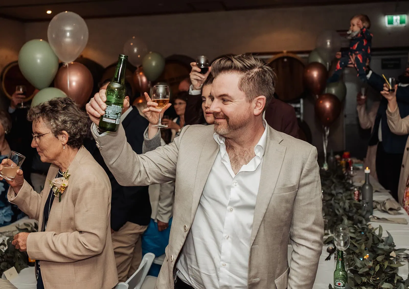grand cru estate wedding - isabella & nick 158 Indoor celebration with friends toasting drinks in a cozy setting.