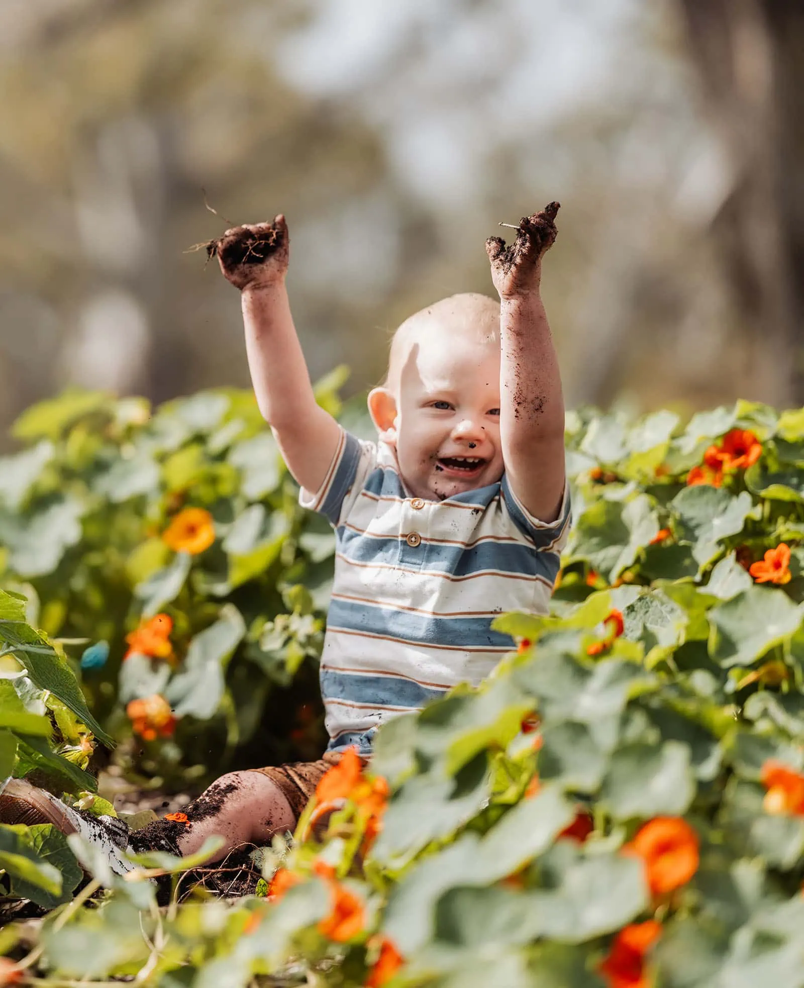southern parklands family photography 38 Child playing joyfully in a vibrant garden, smiling and surrounded by colorful flowers.