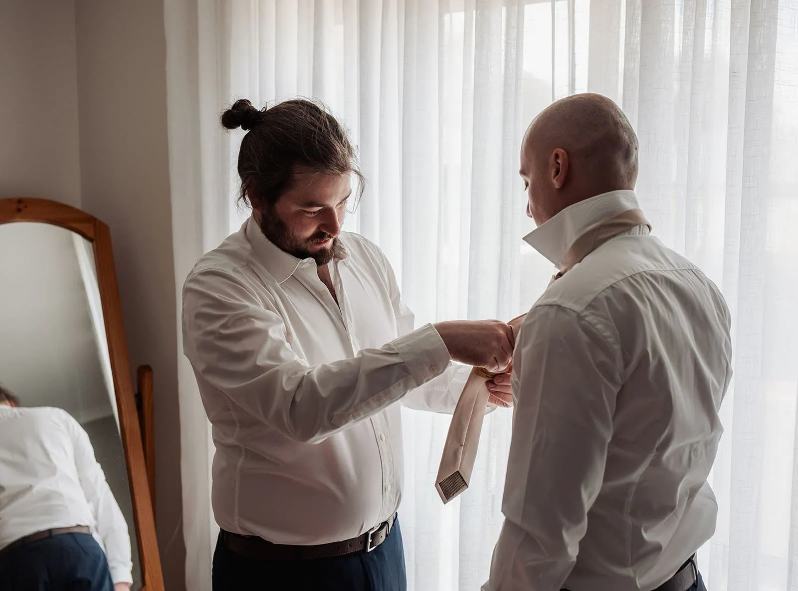 grand cru estate wedding - isabella & nick 97 Men preparing in formal attire in a stylish room.
