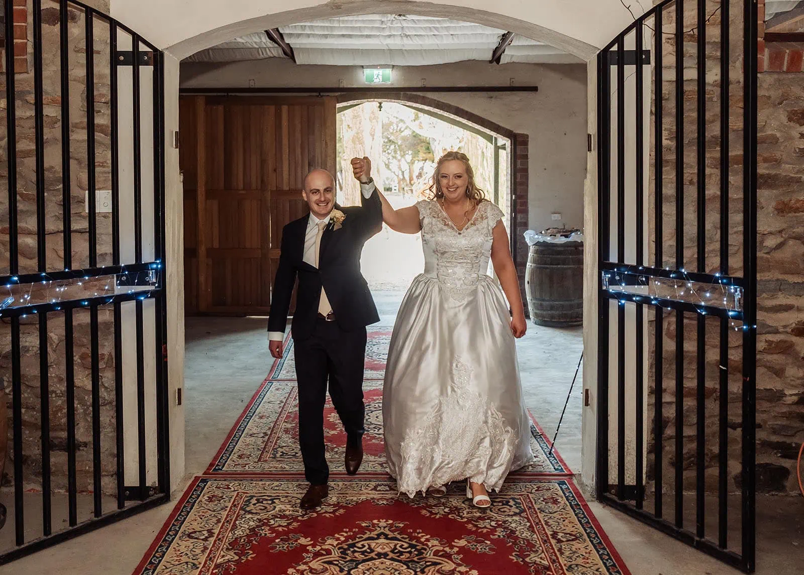 grand cru estate wedding - isabella & nick 155 Rustic wedding entrance with newlywed couple under archway.