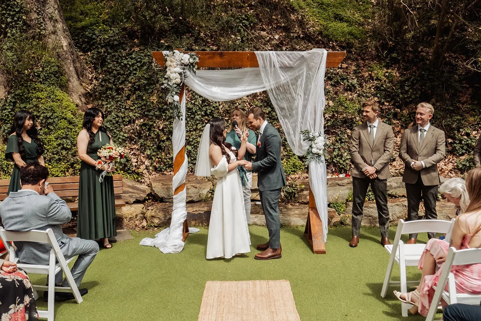 utopia waterfall gully wedding - sally & ben 221 Elegant outdoor wedding ceremony under sunny skies with floral decorations.